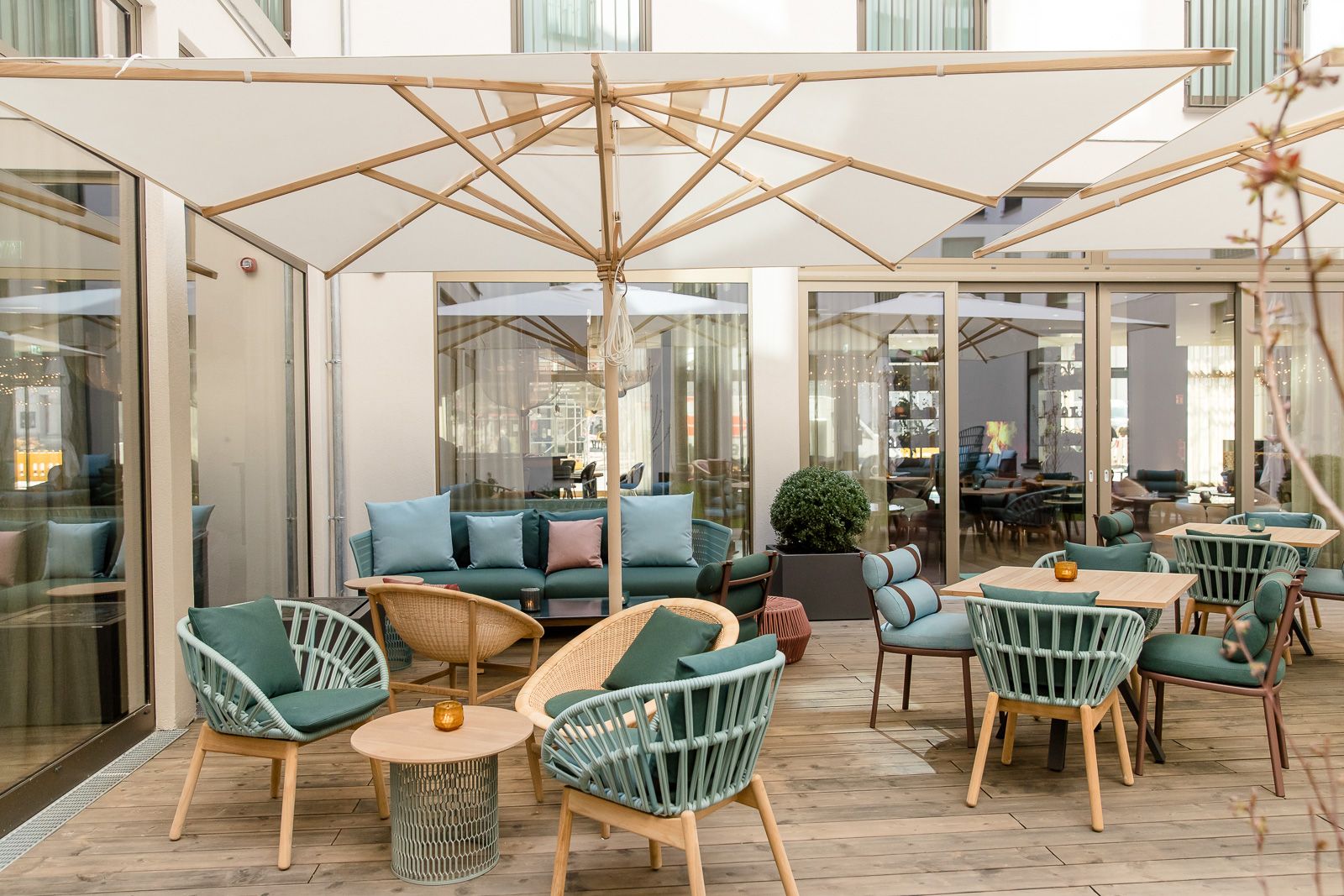 Hotel Aachen Motel One Außenbereich mit Sitzmöglichkeiten und Sonnenschirm auf großer Terrasse