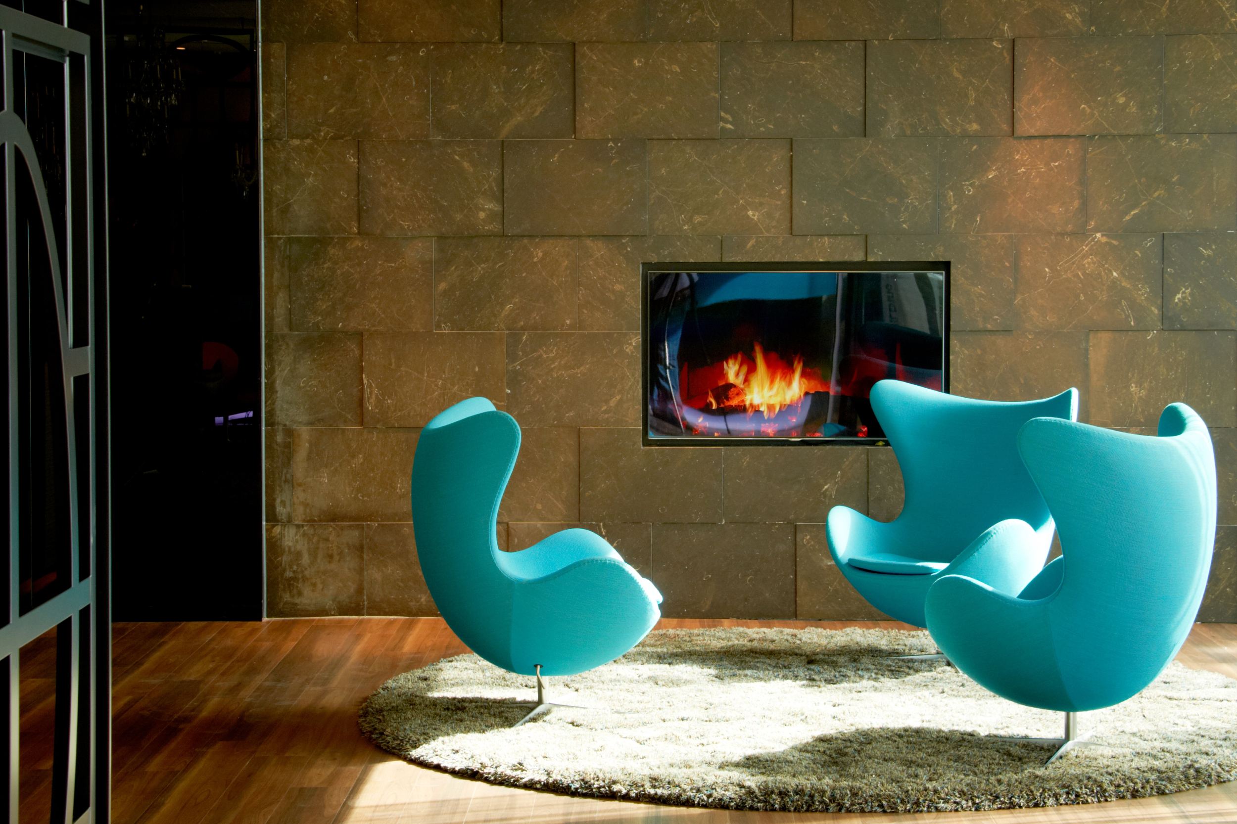hotel Amsterdam Motel One three egg chairs in front of a TV with a fireplace image