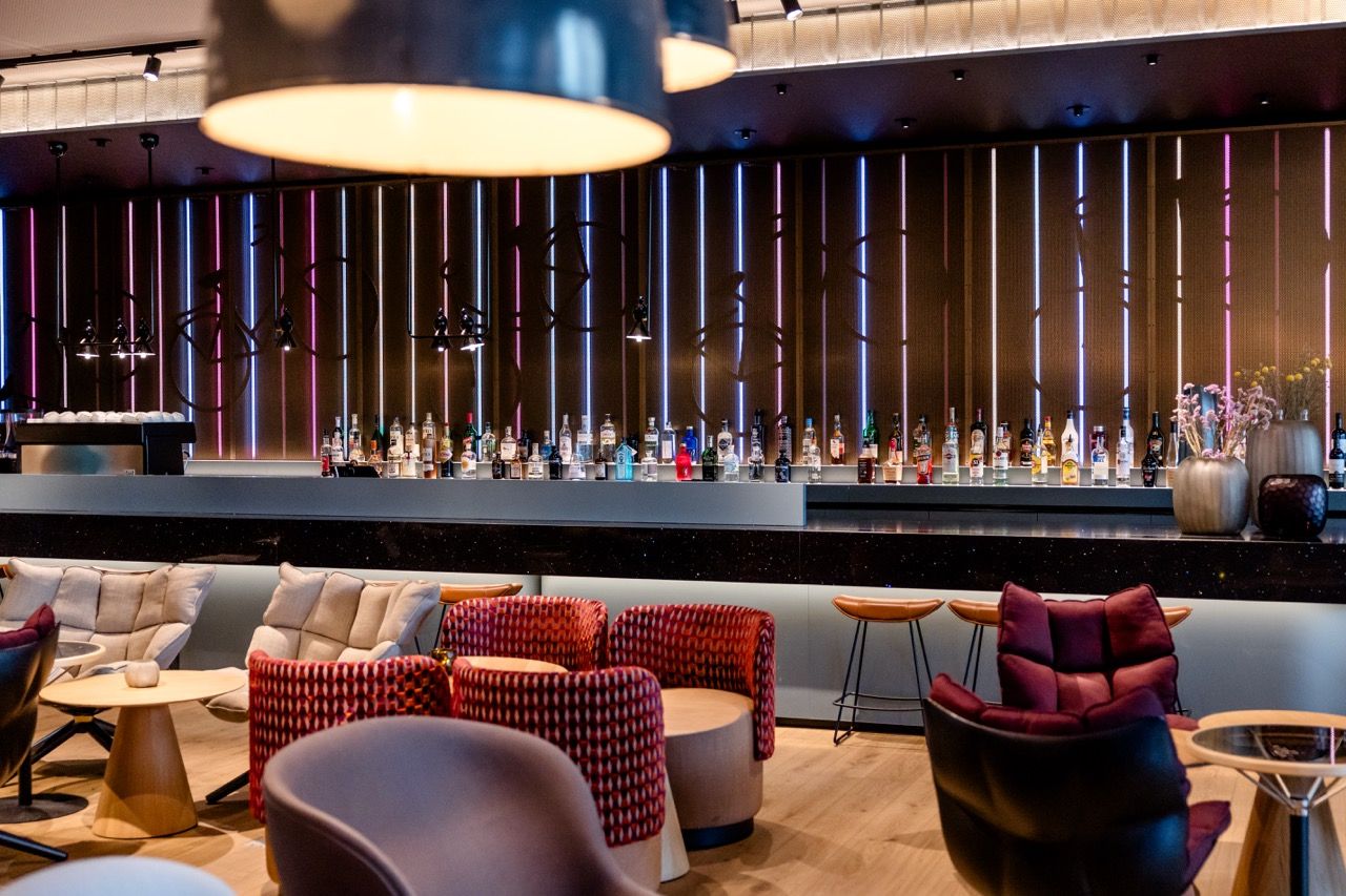 Moderne Hotelbar mit stilvoller Beleuchtung, bequemen Sesseln und Hockern, eleganter Getränkeauswahl und warmem, einladendem Ambiente für entspannte Abende.