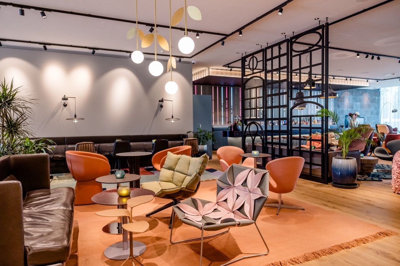 Moderne Lounge mit stilvollen Sesseln und Sofas, warmem Licht und offenen Raumstrukturen, die zum Entspannen und geselligen Beisammensein einladen.