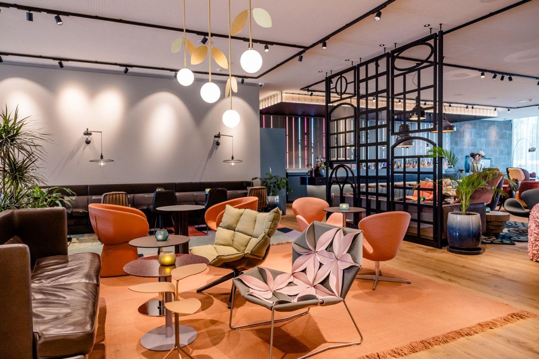 Moderne Lounge mit stilvollen Sesseln und Sofas, warmem Licht und offenen Raumstrukturen, die zum Entspannen und geselligen Beisammensein einladen.