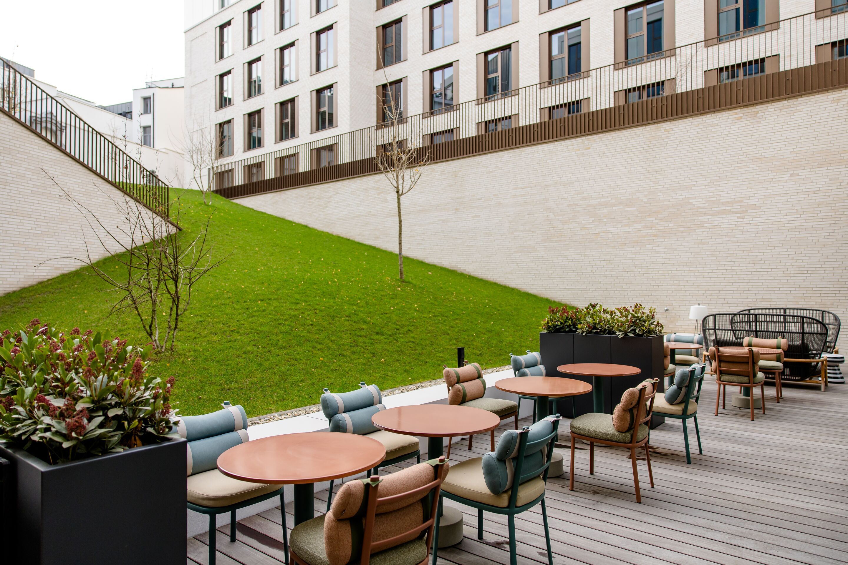 Designhotel Antwerpen Motel One Terrasse mit Sitzgelegenheiten sowie große grüne Rasenfläche im Hintergrund