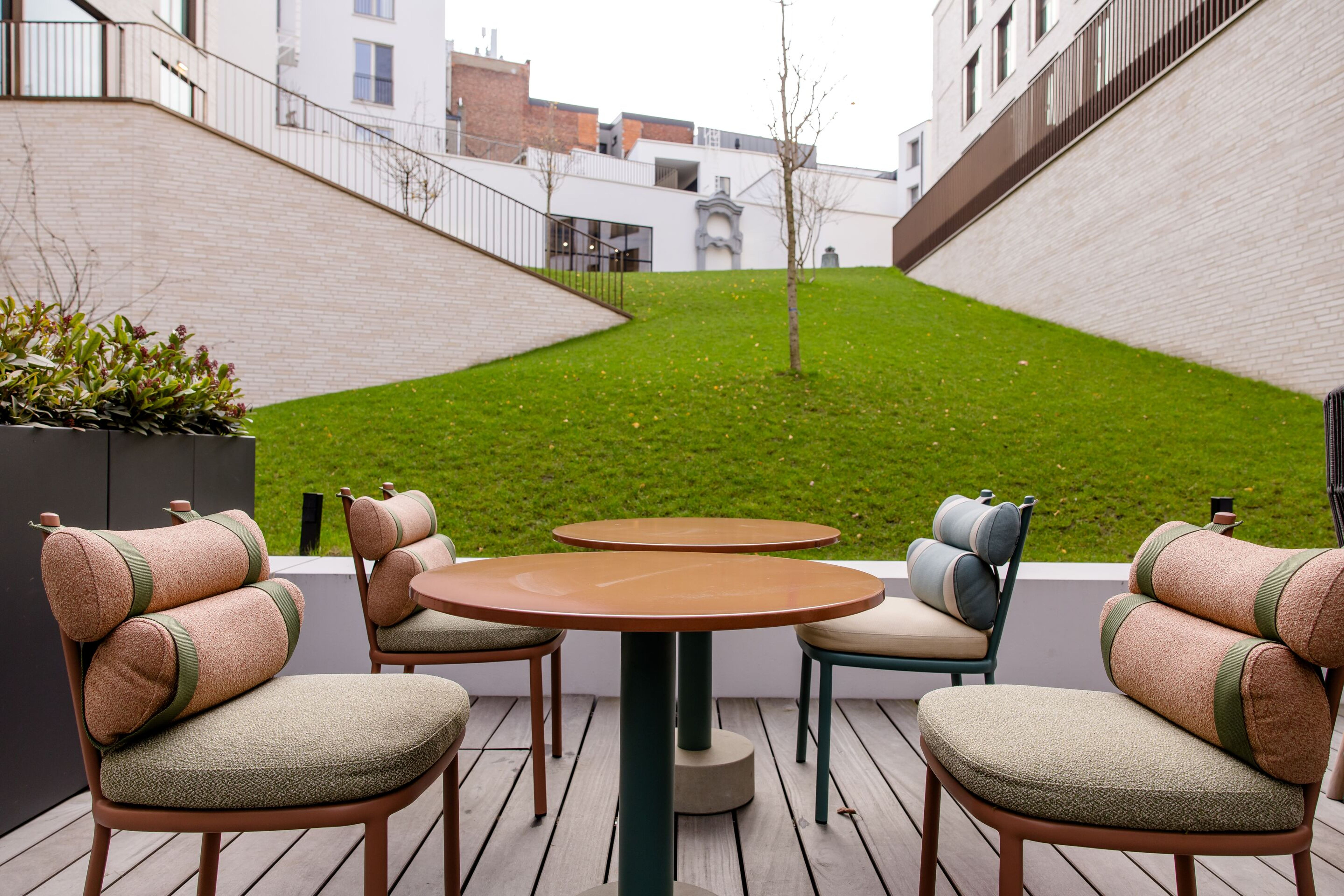 Hotel Antwerpen Motel One Außenbereich mit Blick auf vier Stühle und zwei Tische sowie eine große Rasenfläche Hotel Antwerpen Motel One Außenbereich mit Blick auf vier Stühle und zwei Tische sowie eine große Rasenfläche