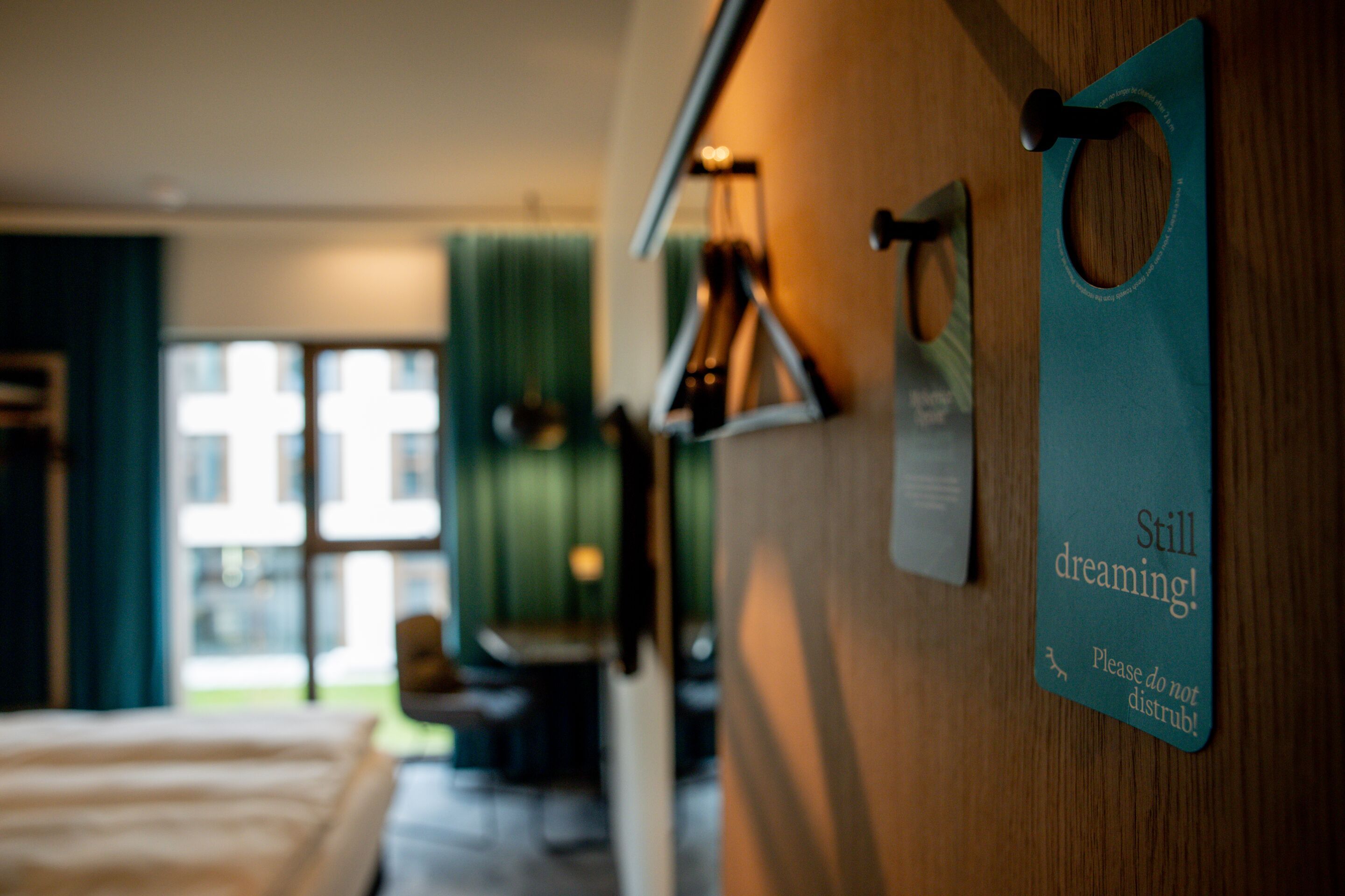 Hotel Antwerpen Motel One Blick in helles Zimmer mit Nahaufnahme auf Türschild mit der Aufschrift "Still dreaming!"