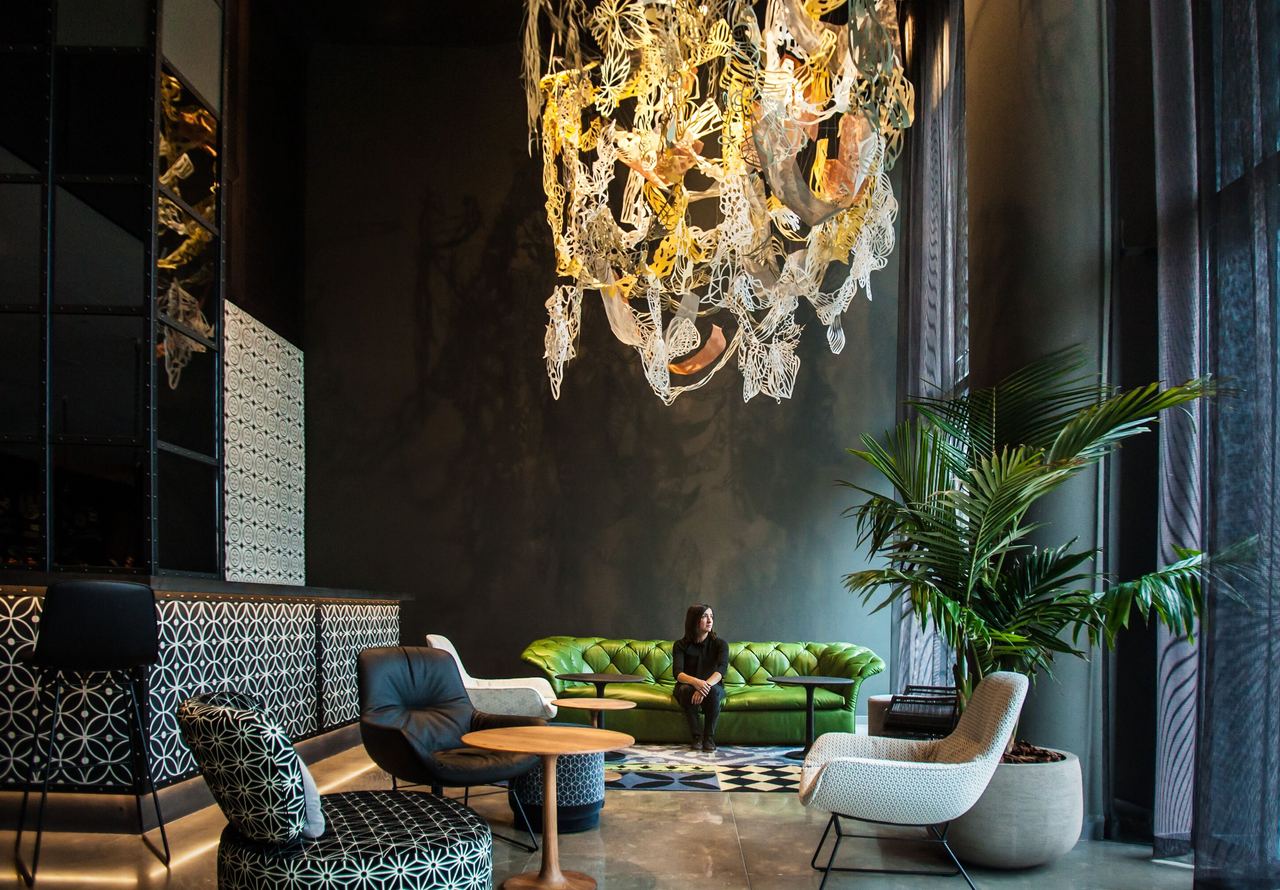 Hotel Barcelona Ciutadella Motel One Künstlerin Anaïs Senli sitzt in heller Lounge auf einem hellgrünen Sofa