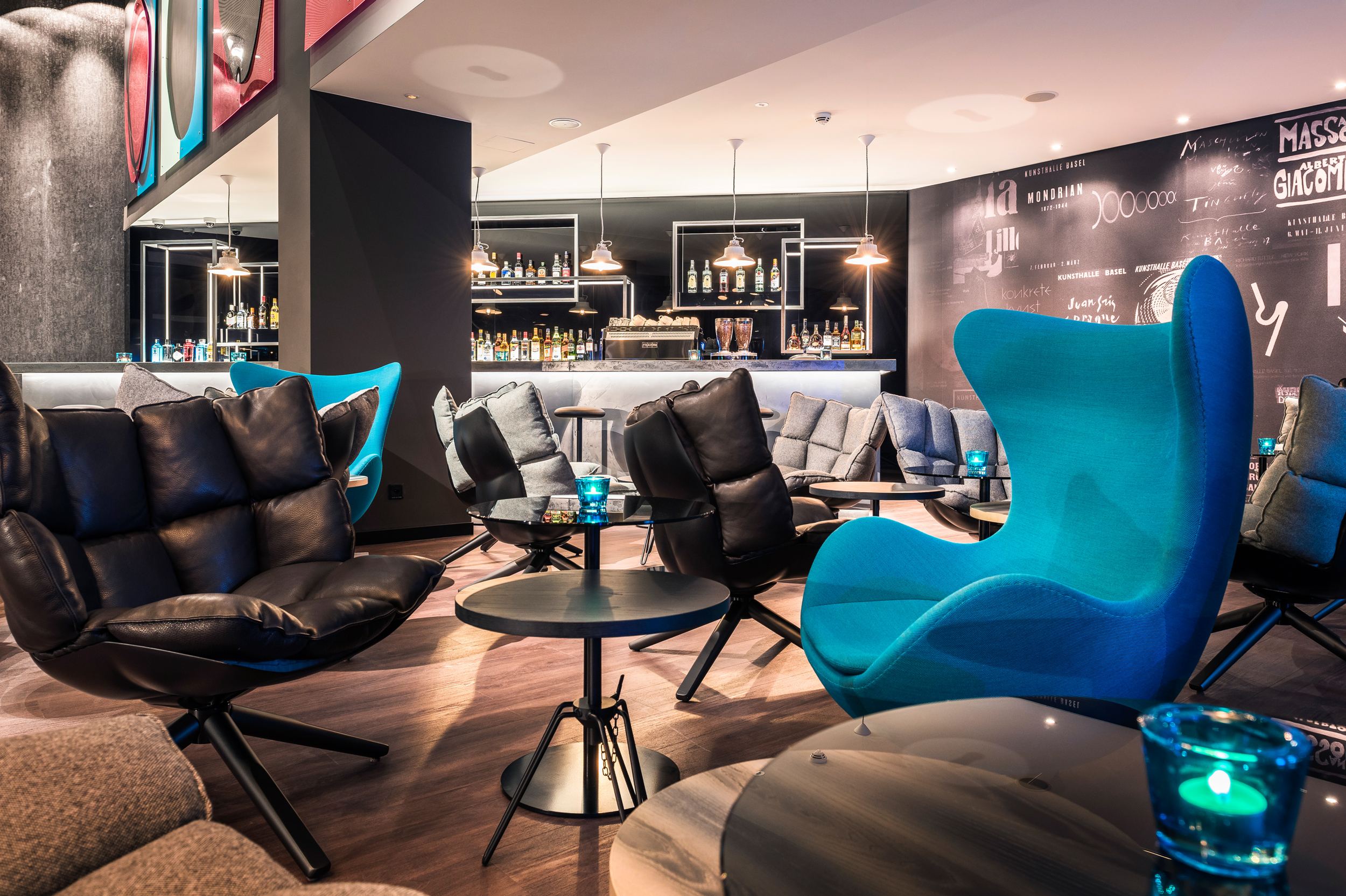 Designhotel Basel Motel One Lounge mit Egg Chair und weiteren Stühlen im Vordergrund sowie Bar im Hintergrund
