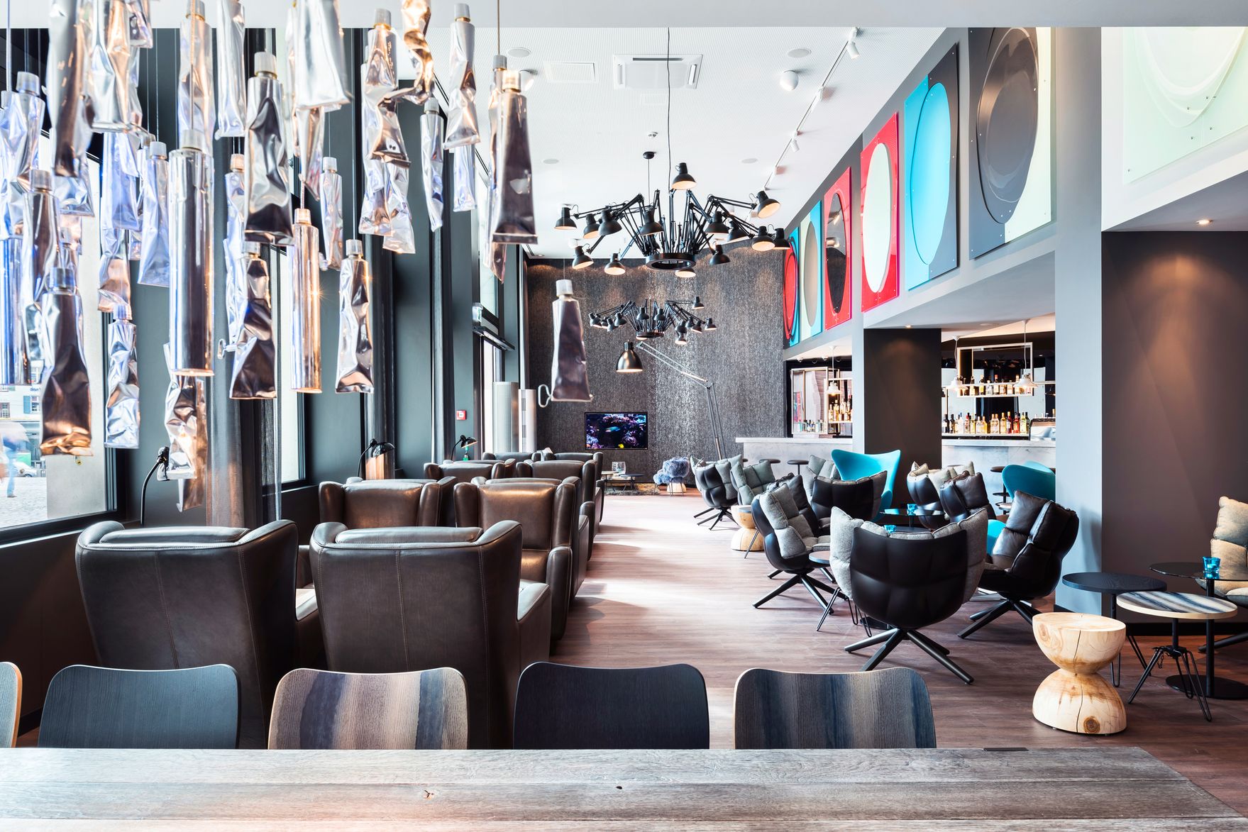 Designhotel Basel Motel One Blick in helle Lounge mit mehreren Sesseln und die Bar im Hintergrund