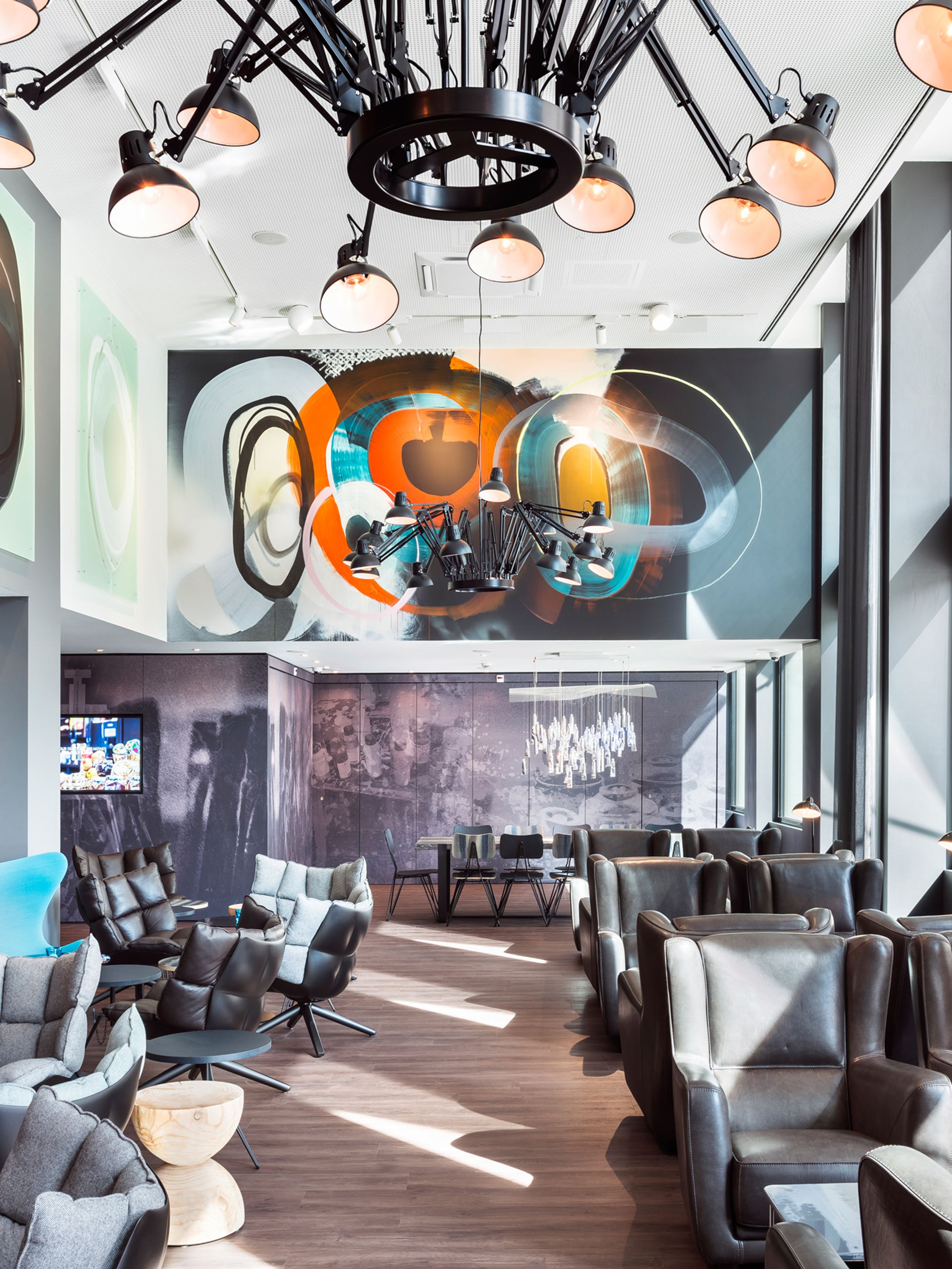 Designhotel Basel Motel One Lounge mit Sonneneinstrahlung durch bodentiefe Fenster und mehrere Sitzgelegenheiten