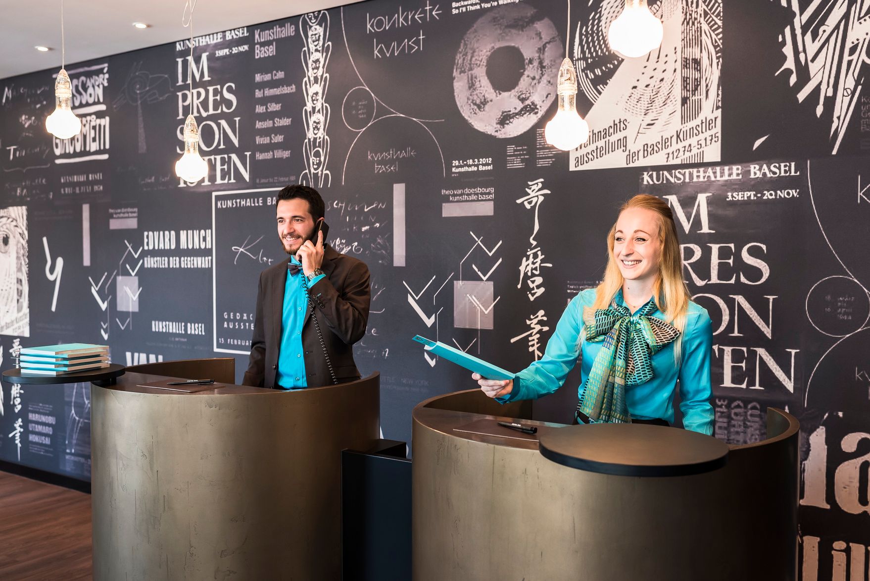 Designhotel Basel Motel One Rezeption mit zwei Mitarbeitenden bei der Arbeit
