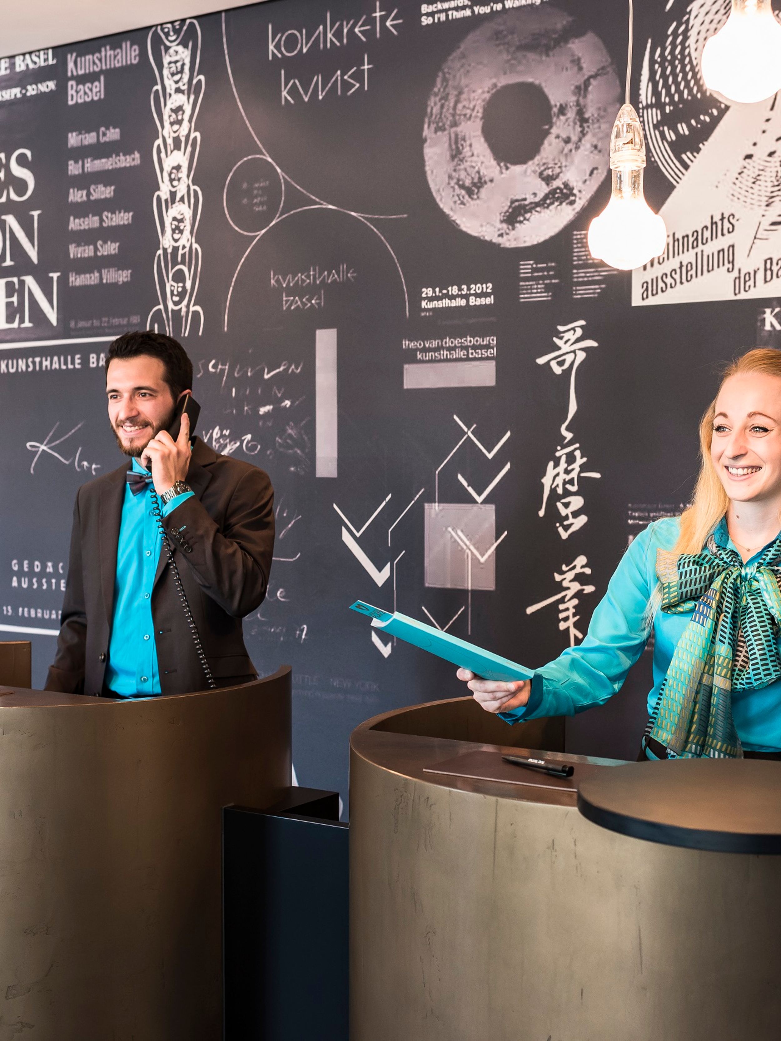 Designhotel Basel Motel One Rezeption mit zwei Mitarbeitenden bei der Arbeit