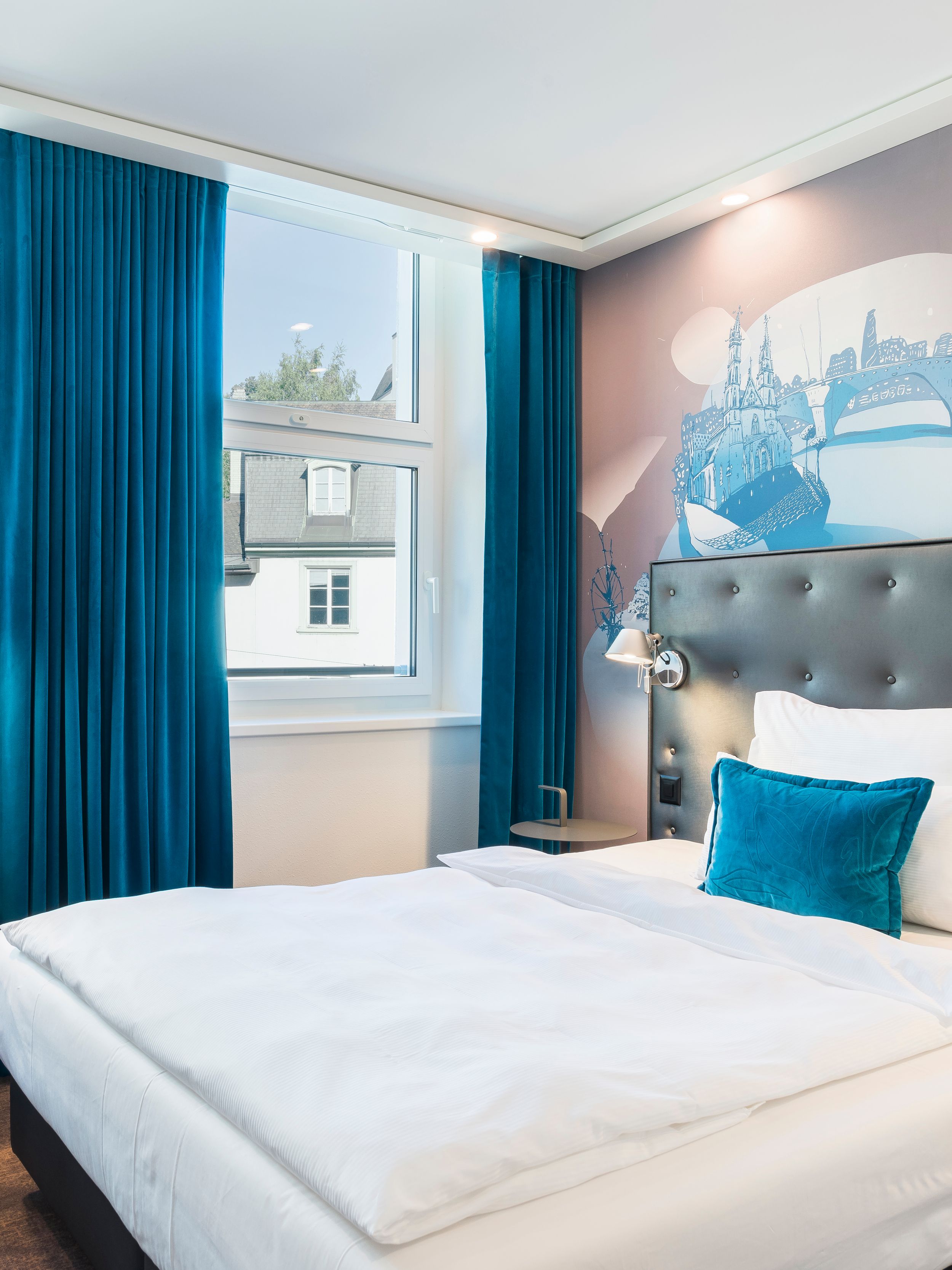 designhotel Basel Motel One side view into a bright room with a bed and armchair