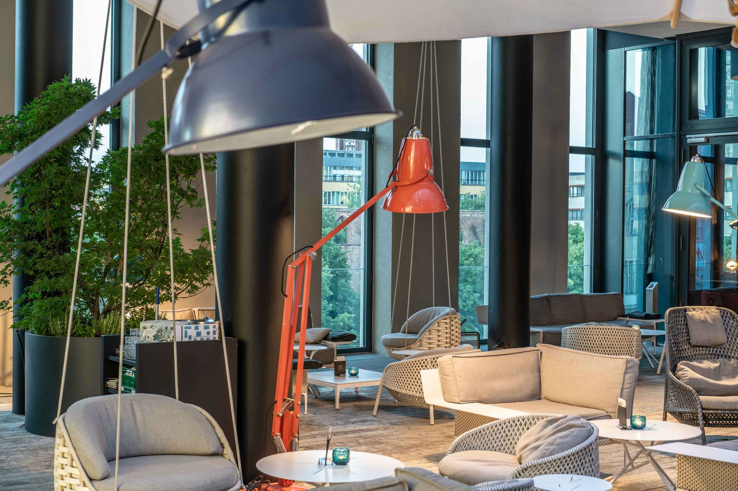 Hotel Berlin Alexanderplatz Motel One lichtdurchflutete Lounge mit mehreren Sitzgelegenheiten sowie schwingenden Stühlen, die an der Decke befestigt sind