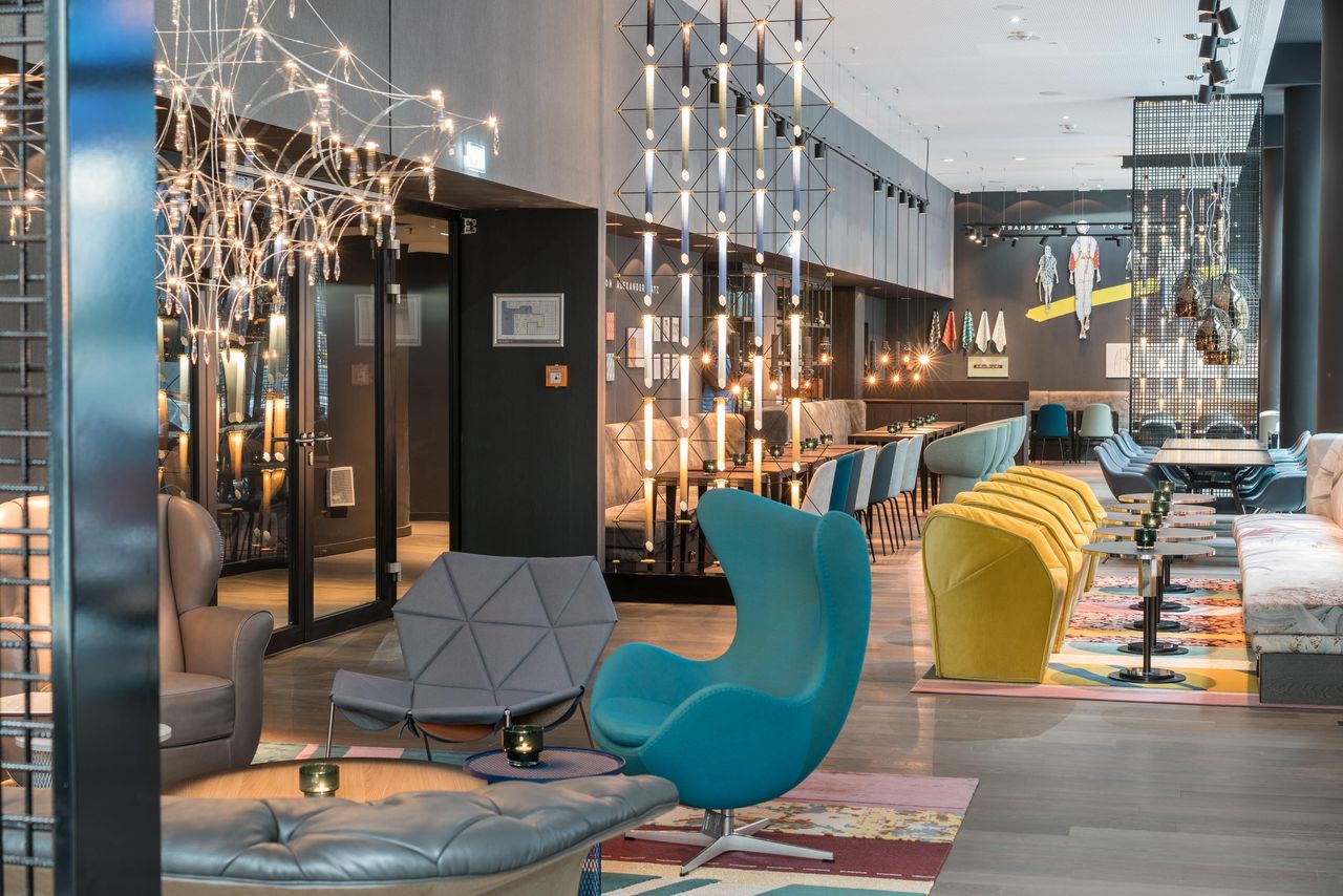 hotel Berlin Alexanderplatz Motel One light-filled lounge with several seating areas and a turquoise Egg Chair in the foreground