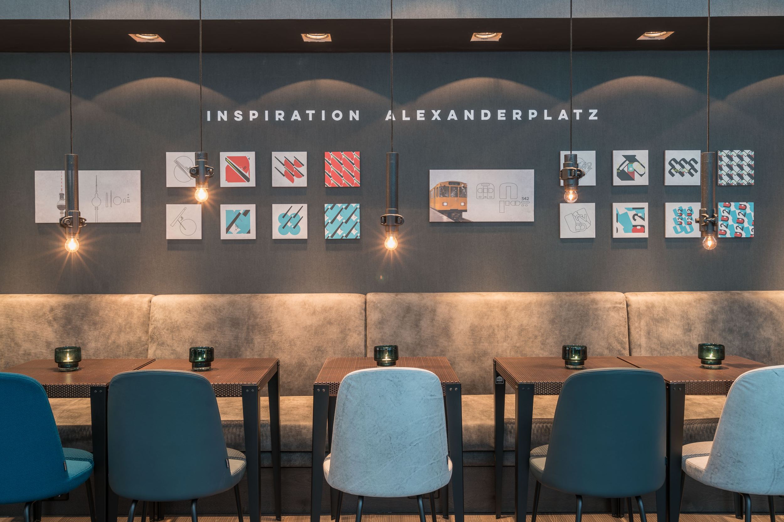 Hotel Berlin Alexanderplatz Motel One Essbereich mit mehreren Tischen und Stühlen sowie Schriftzug Inspiration Alexanderplatz an der Wand