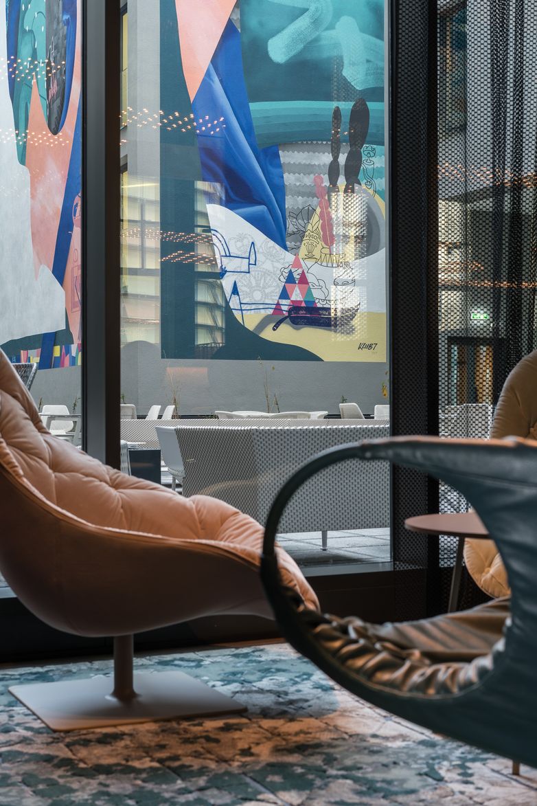 Hotel Berlin Alexanderplatz Motel One Sessel vor bodentiefem Fenster mit Blick auf den möblierten Außenbereich