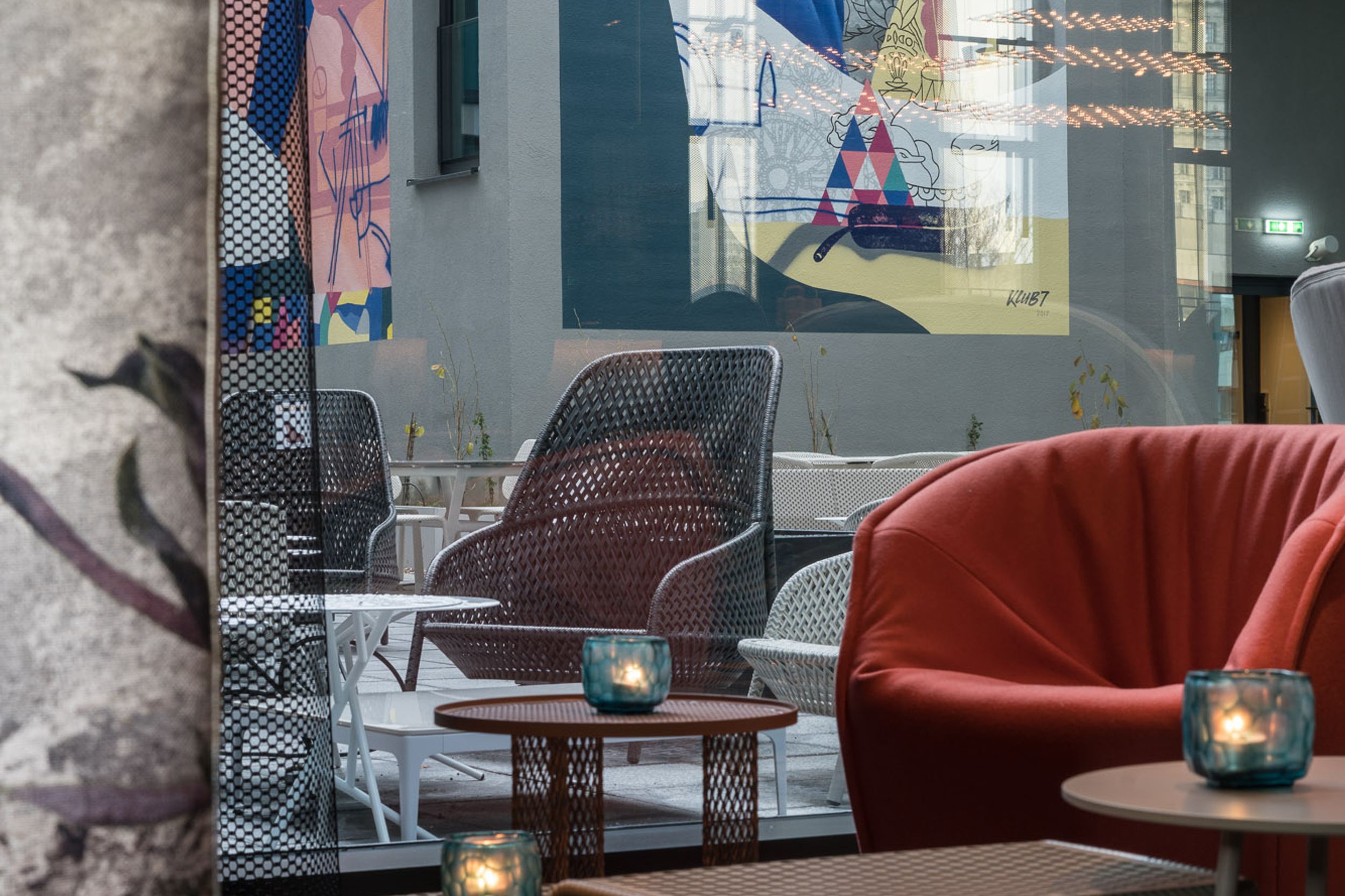 Designhotel Berlin Alexanderplatz Motel One Lounge mit Blick durch bodentiefe Fensterfront auf den Außenbereich des Hotels mit Sitzgelegenheiten