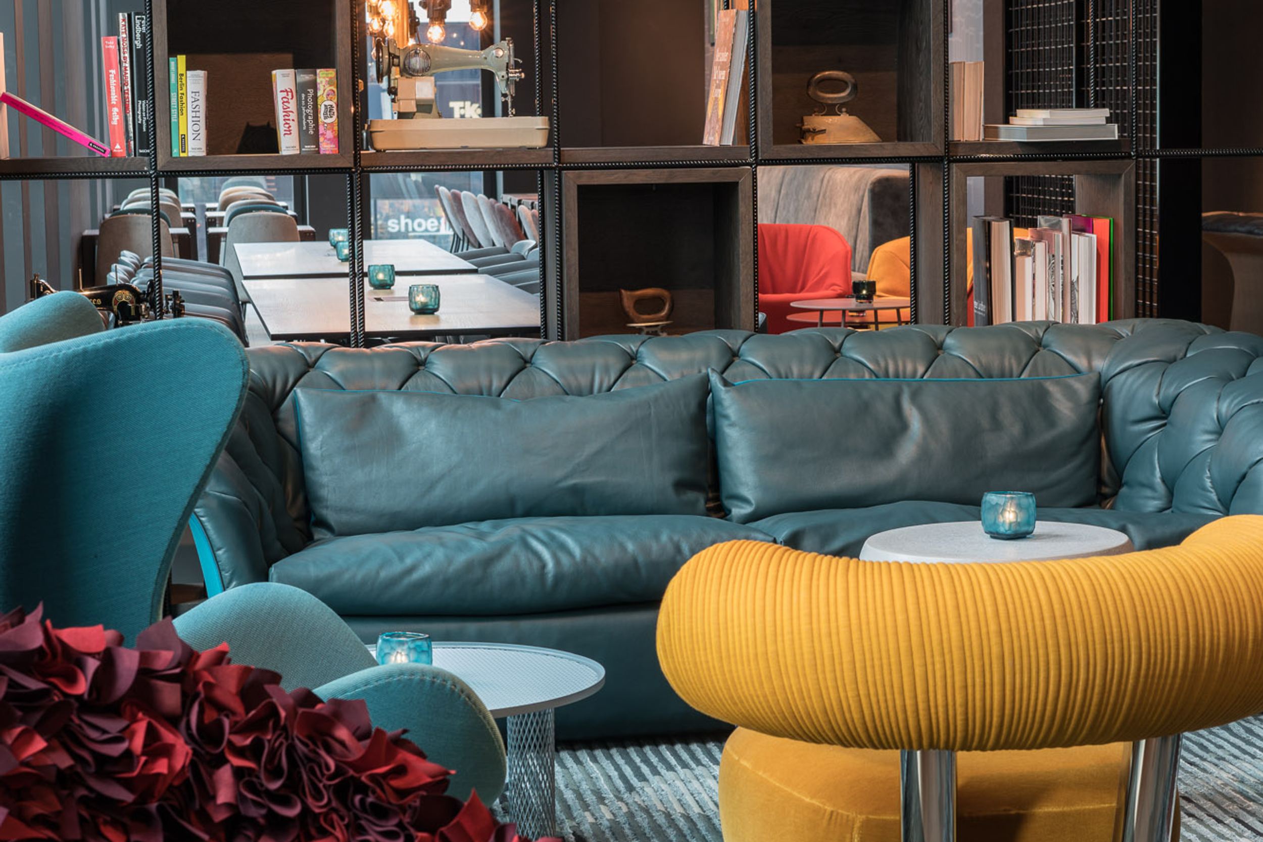hotel Berlin Alexanderplatz Motel One light-filled lounge with large sofa, armchairs, egg chair, and open shelving with decorative items