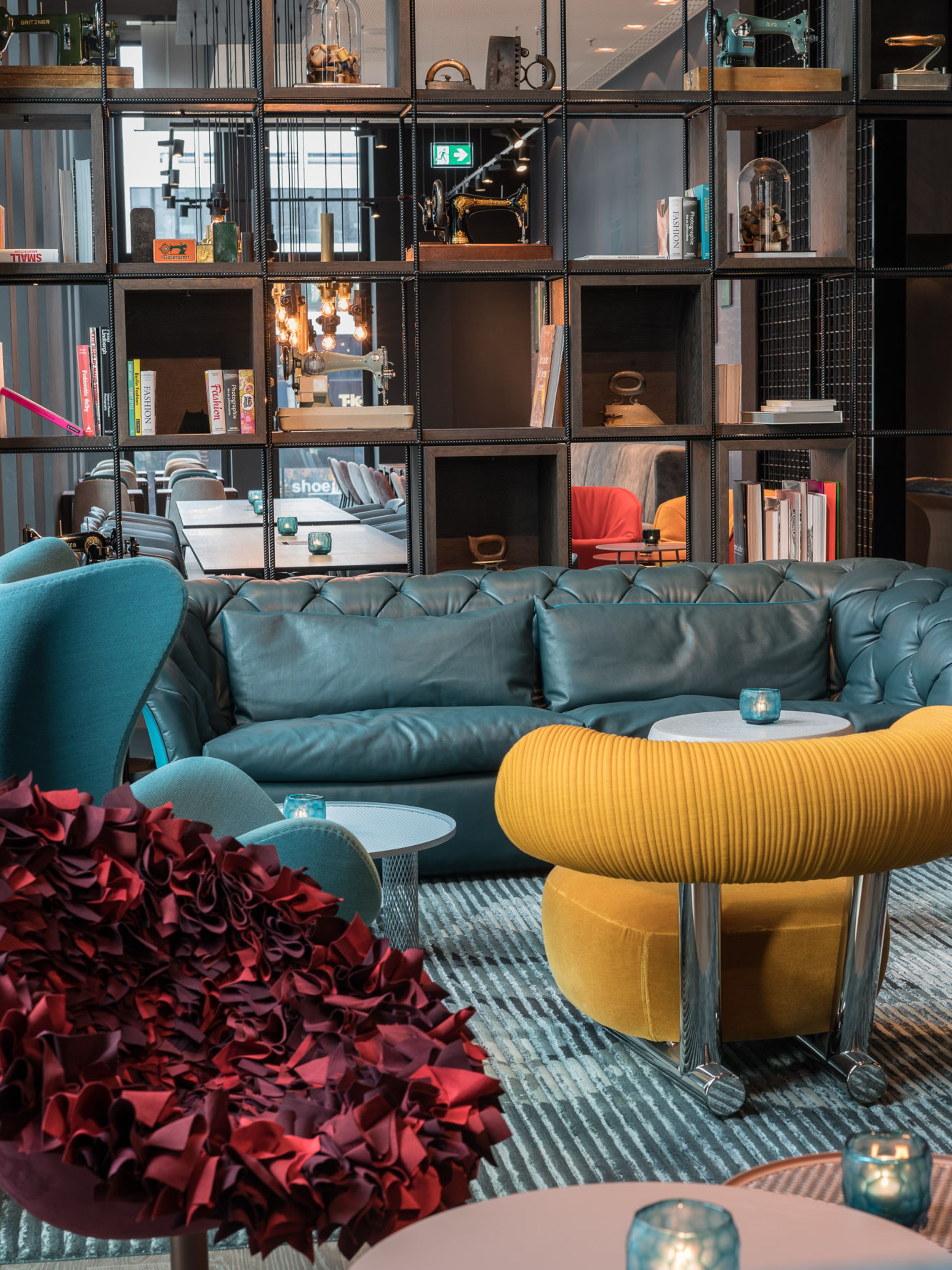 Hotel Berlin Alexanderplatz Motel One lichtdurchflutete Lounge mit großem Sofa, Sesseln, Egg Chair sowie offenes Regal mit Dekoration