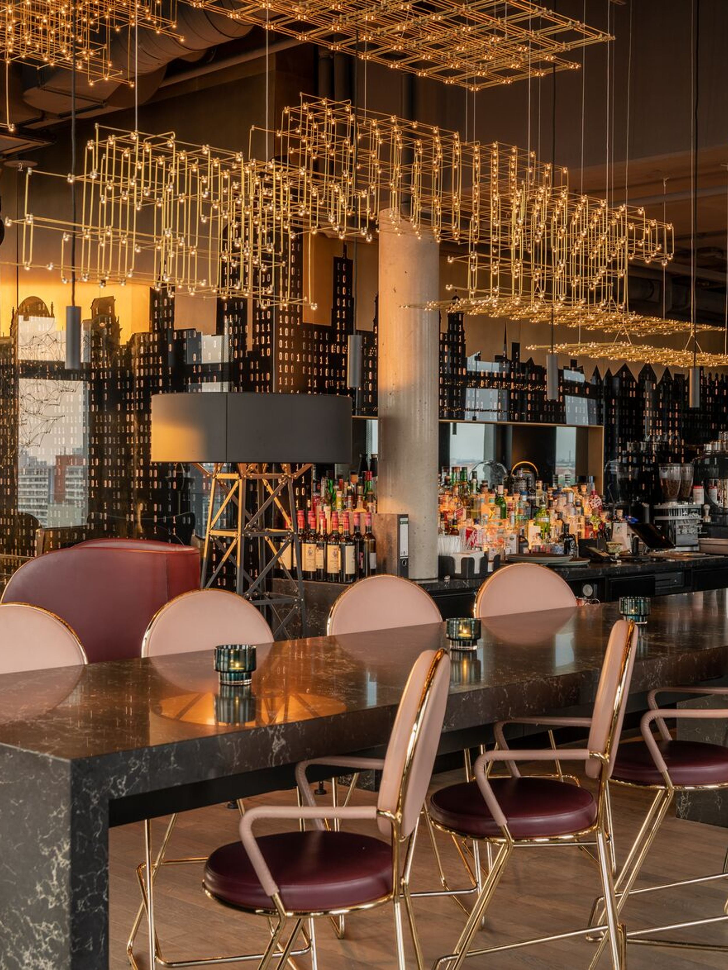 Hotel Berlin Alexanderplatz Motel One helle Lounge mit langem Hochtisch und Stühlen im Vordergrund sowie Bar im Hintergrund