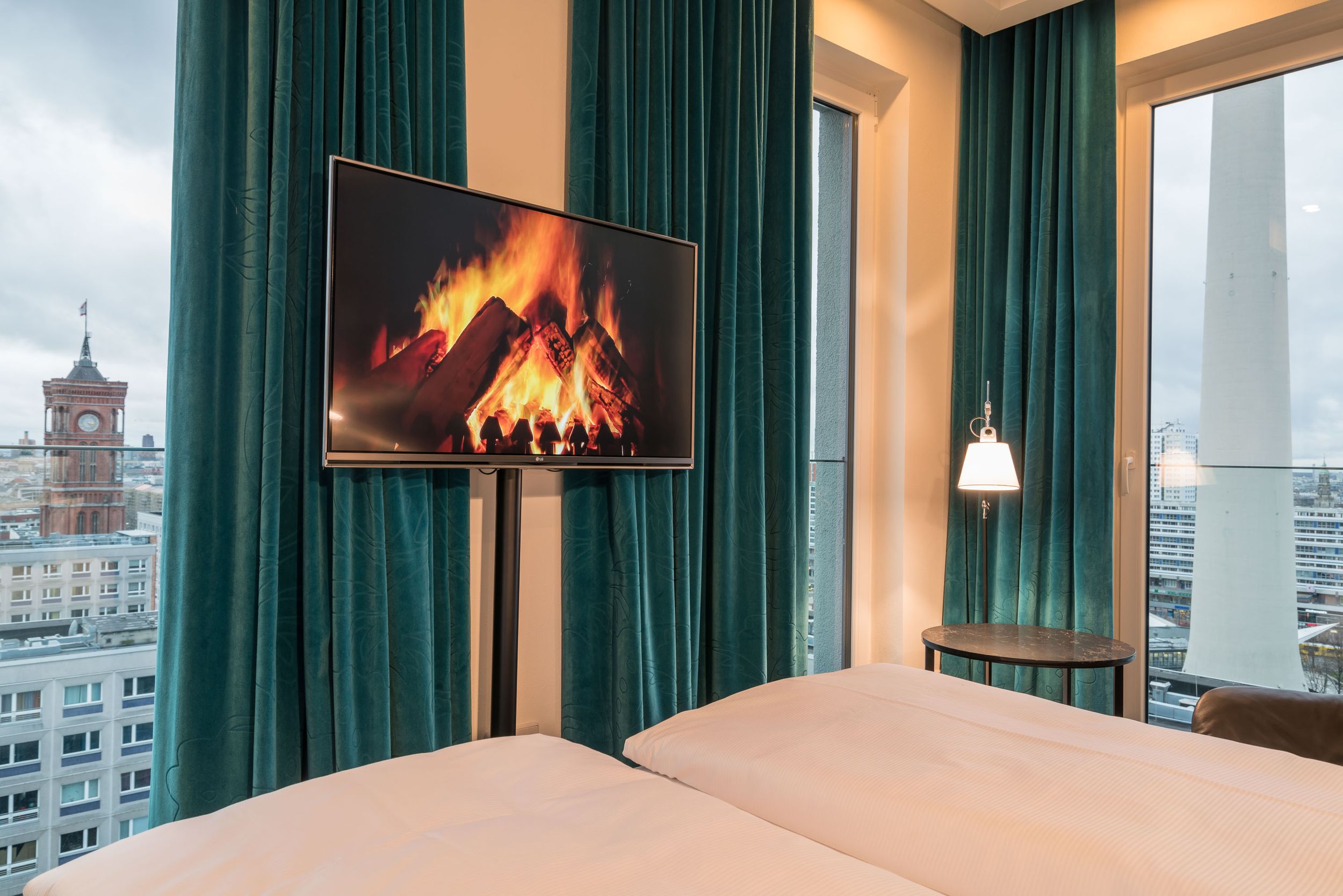 Hotel Berlin Alexanderplatz Motel One Eckzimmer im oberen Stockwerk mit Bett, Fernseher und bodentiefen Fenstern mit Ausblick über die Stadt