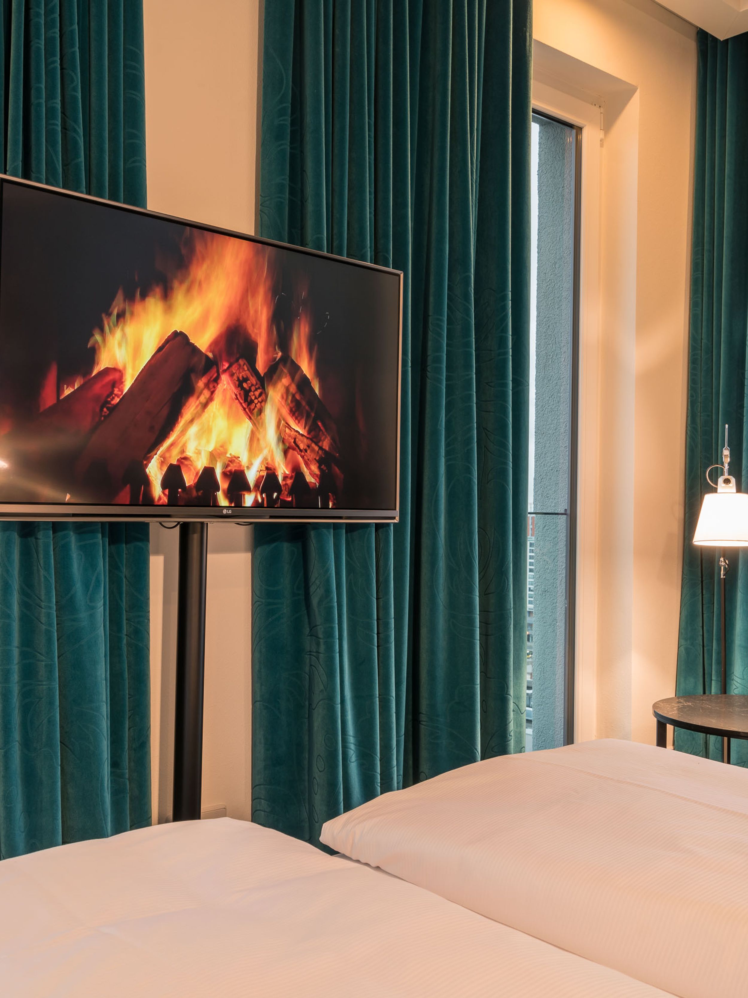 Hotel Berlin Alexanderplatz Motel One Eckzimmer im oberen Stockwerk mit Bett, Fernseher und bodentiefen Fenstern mit Ausblick über die Stadt