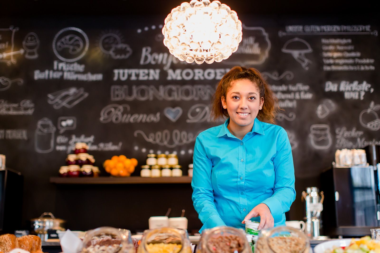 Designhotel Berlin Bellevue Motel One lächenlnde Mitarbeiterin des Hotels am Frühstücksbuffet