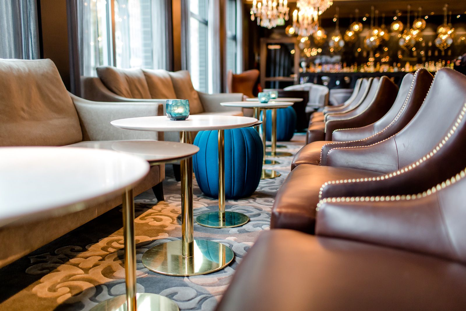 Hotel Berlin Bellevue Motel One lichtdurchflutete Lounge mit mehreren Tischen und Stühlen sowie Bar im Hintergrund