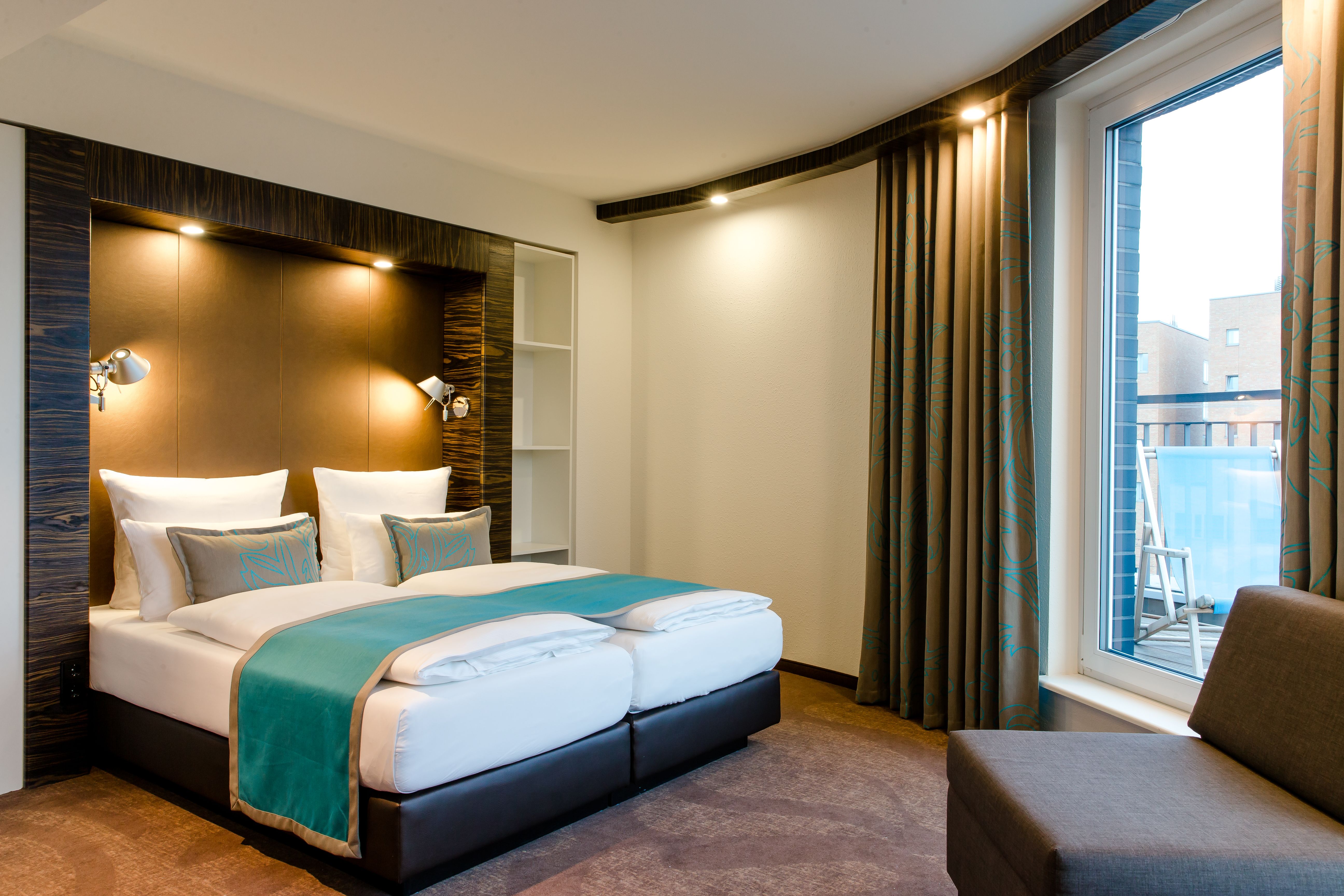 Hotel Berlin Bellevue Motel One großes Doppelbett und Sessel in hellem Zimmer mit Balkonzugang und Liegestuhl