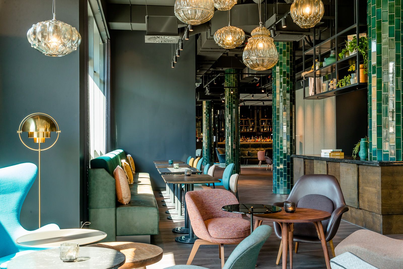 Hotel Berlin Hackescher Markt Motel One lichtdurchflutete Lounge mit mehreren Tischen und Stühlen sowie die Bar im Hintergrund