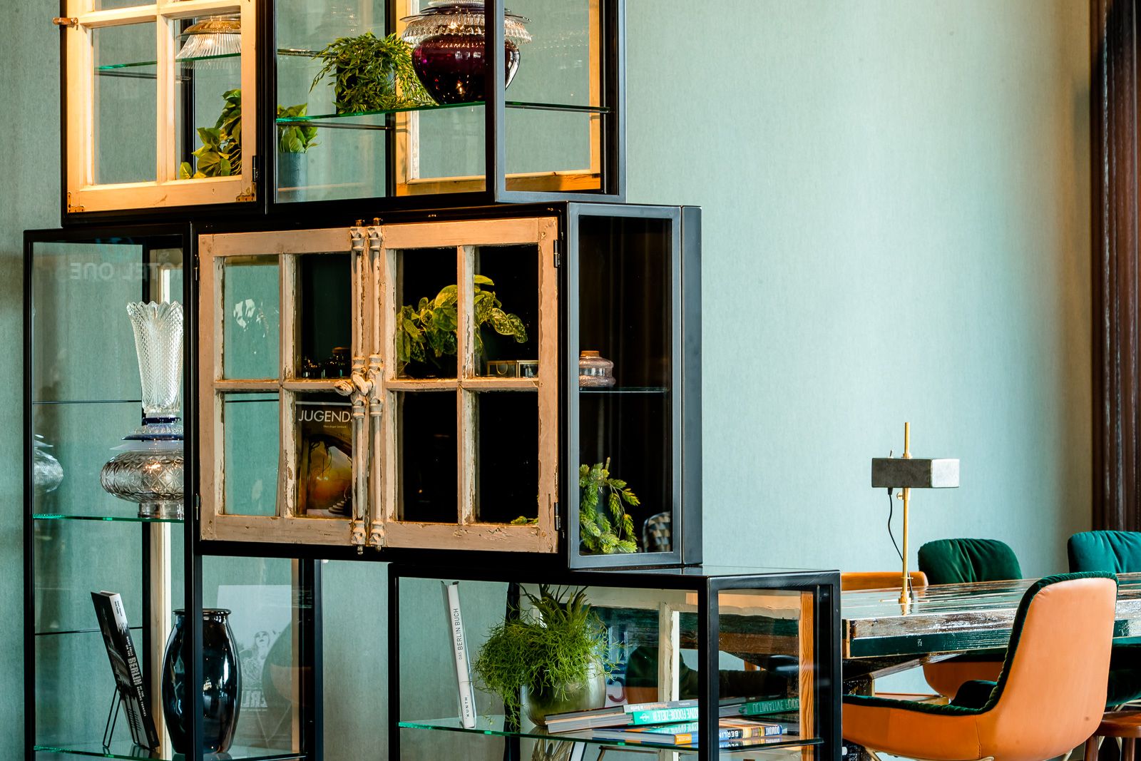 Hotel Berlin Hackescher Markt Motel One Lounge mit Blick auf ein offenes Regal mit Dekoration sowie ein langer Tisch mit Stühlen im Hintergrund