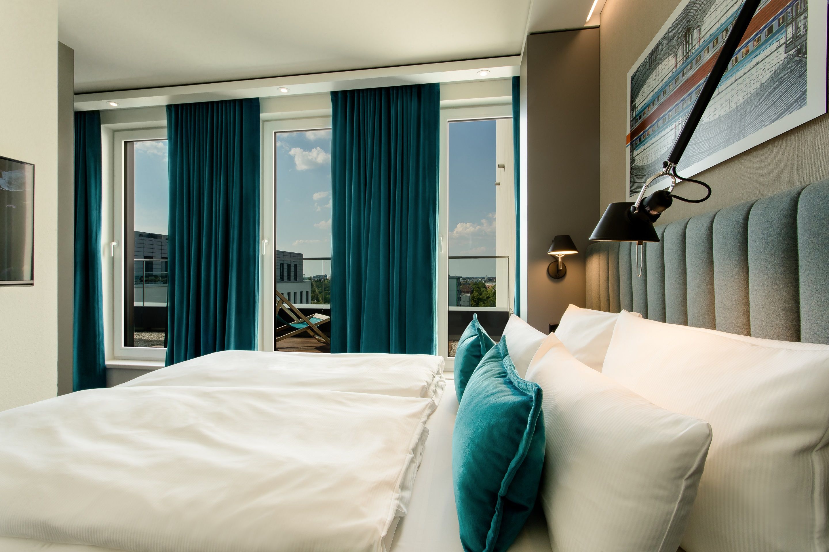 Hotel Motel One Berlin-Hauptbahnhof Gemütliches Hotelzimmer mit großem Doppelbett, stilvollen blauen Vorhängen, frischem Tageslicht und Blick auf eine ruhige Stadtlandschaft. Modernes Ambiente lädt zum Entspannen ein.