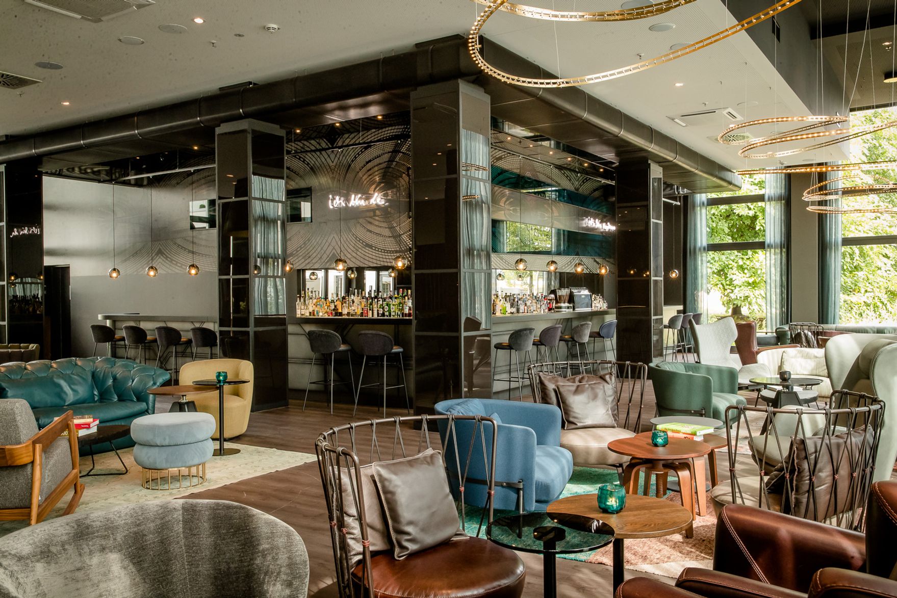 Designhotel Berlin Hauptbahnhof Motel One lichtdurchflutete Lounge mit Sesseln und Beistelltischen sowie große Eckbar