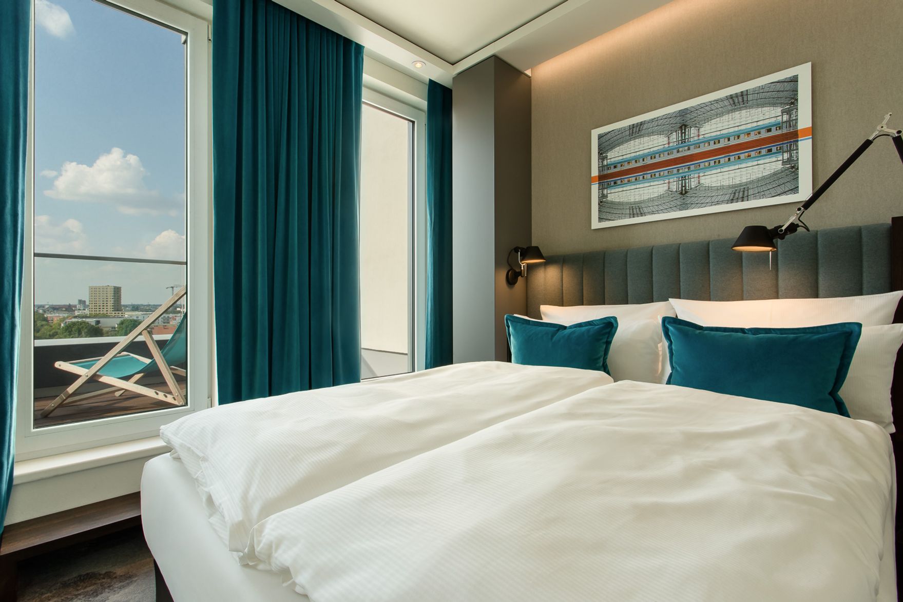 Hotel Berlin Hauptbahnhof Motel One helles Balkonzimmer mit Doppelbett sowie Blick auf einen Liegestuhl auf dem Balkon