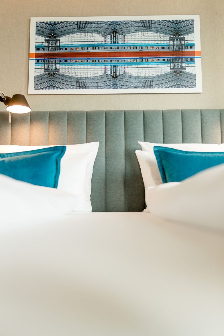 Hotel Berlin Hauptbahnhof Motel One Nahaufnahme auf ein Doppelbett mit zwei Zierkissen in türkis sowie ein Bild an der Wand