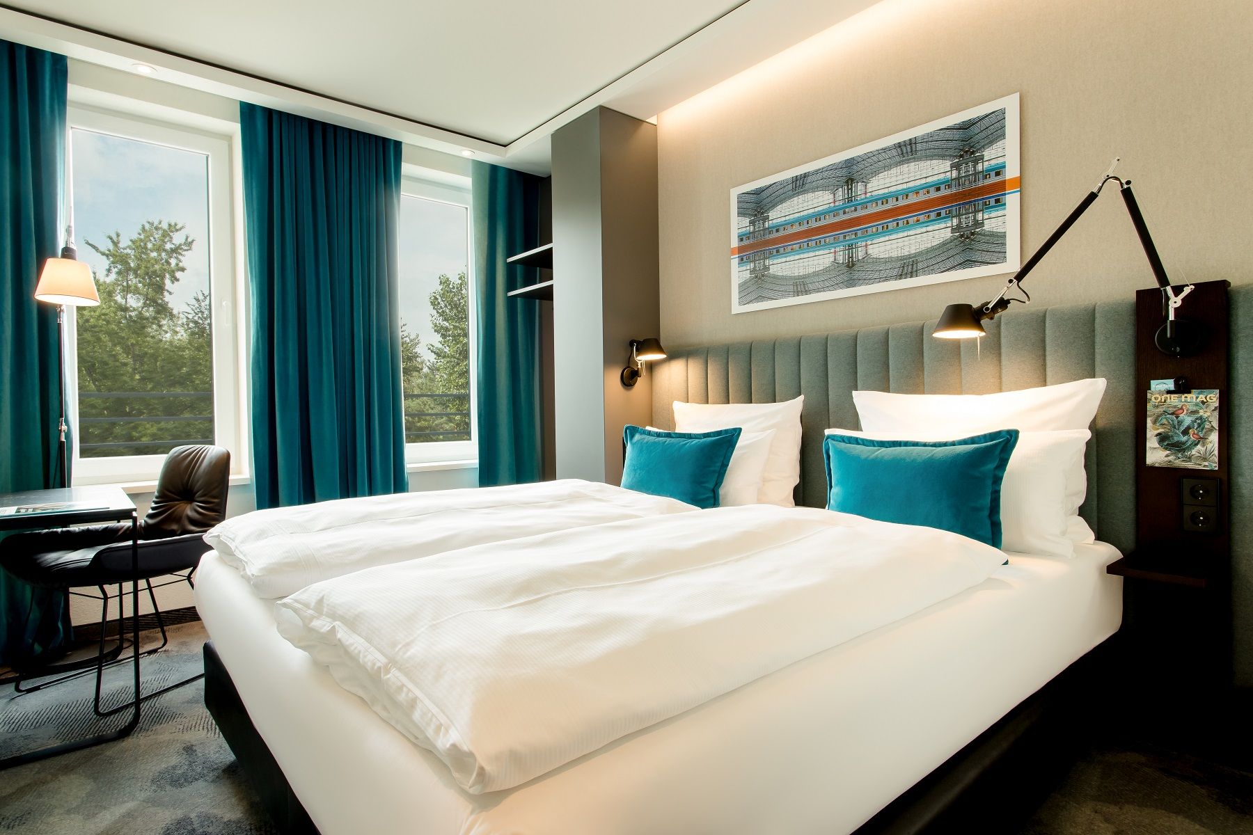 Hotel Berlin Hauptbahnhof Motel One Doppelzimmer mit großem Bett, zwei Fenstern mit viel Tageslicht und ein Tisch mit Stuhl