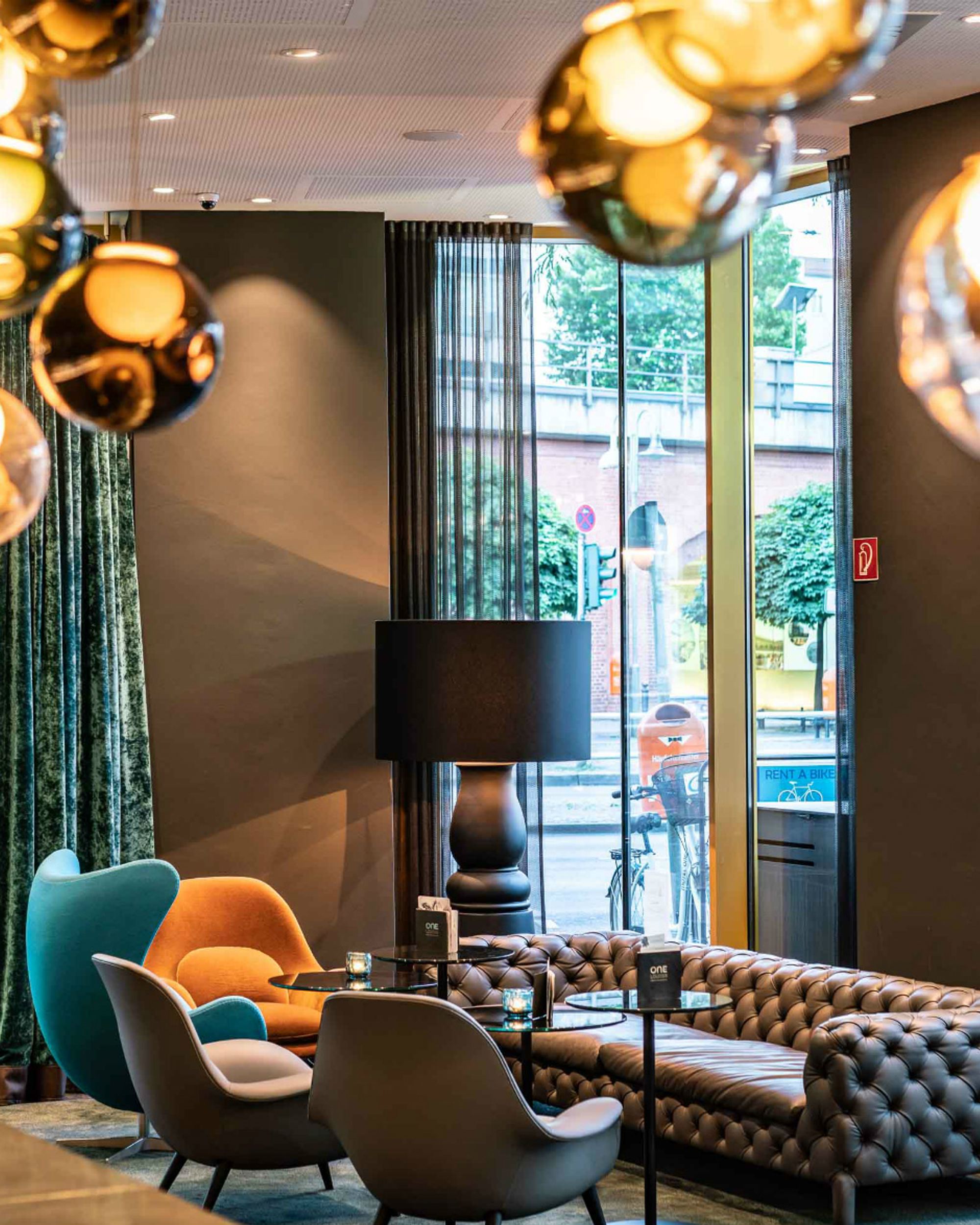 Hotel Berlin Ku’damm Motel One Lounge mit bodentiefen Fenstern und einer Sitzgruppe, bestehend aus Sofa und Sesseln
