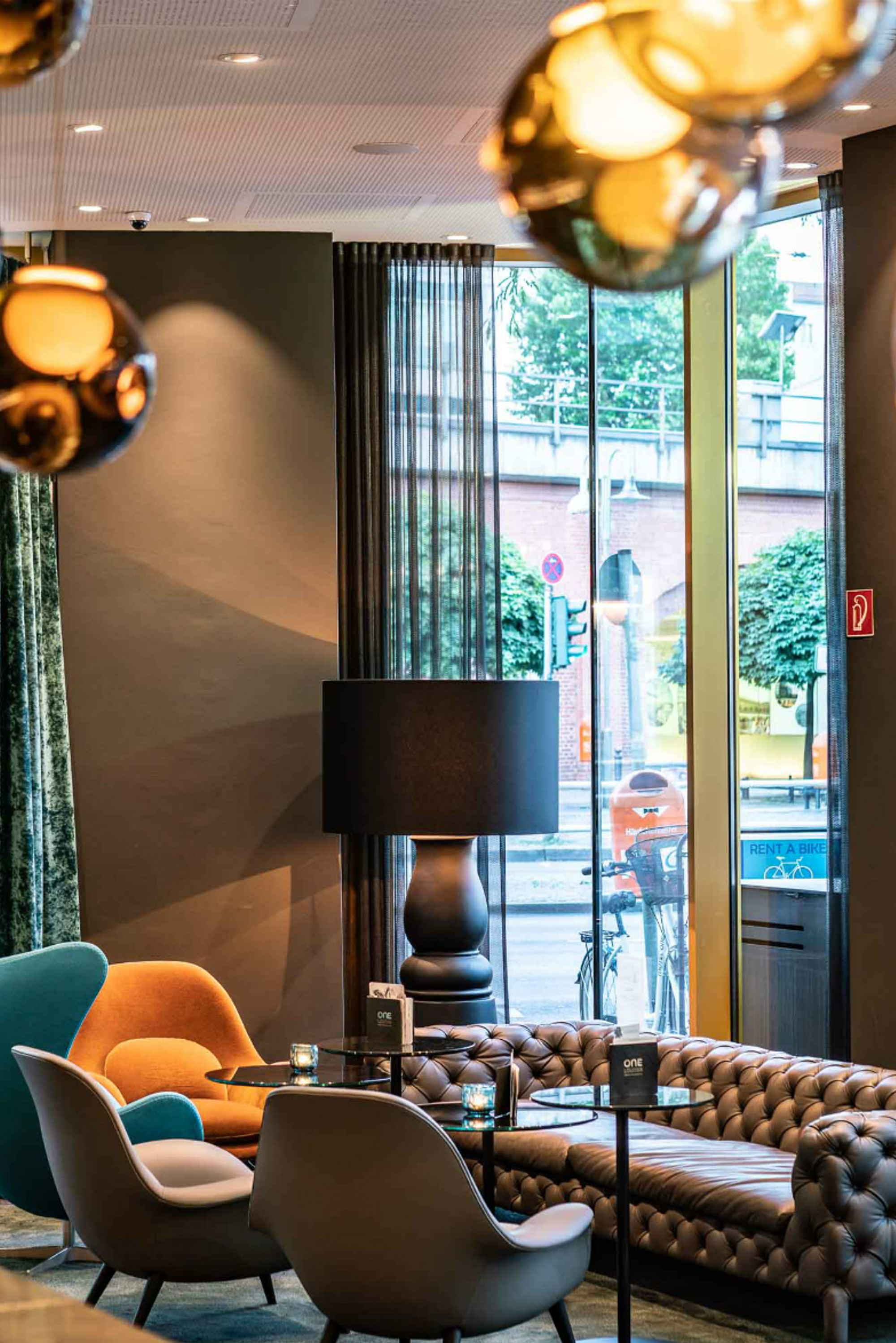 Hotel Berlin Ku’damm Motel One Lounge mit bodentiefen Fenstern und einer Sitzgruppe, bestehend aus Sofa und Sesseln
