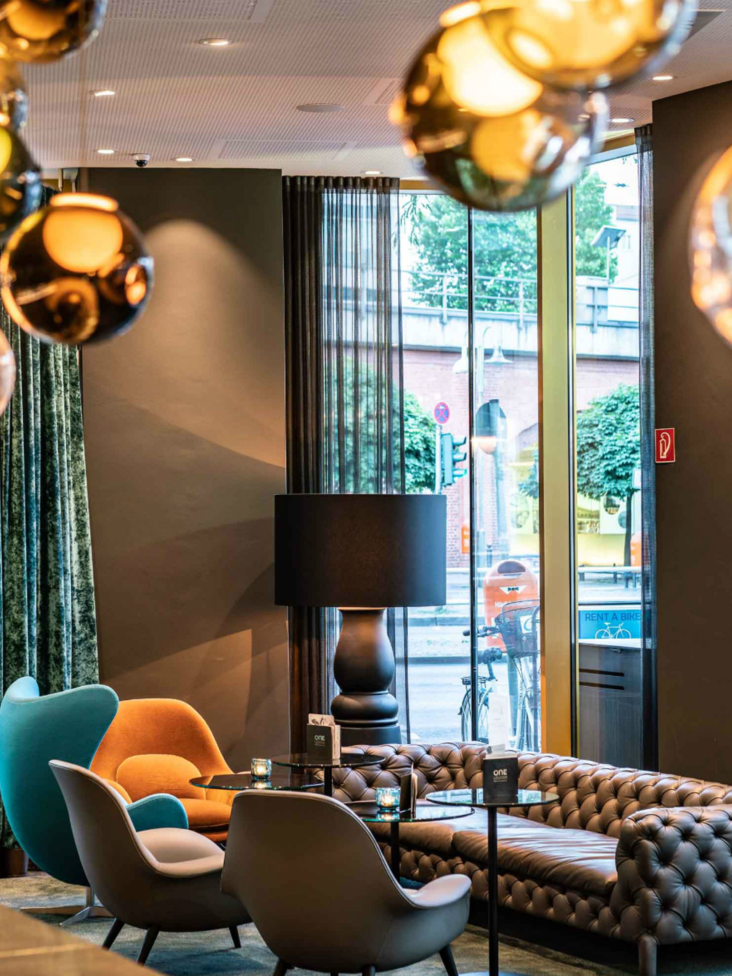 Hotel Berlin Ku’damm Motel One Lounge mit bodentiefen Fenstern und einer Sitzgruppe, bestehend aus Sofa und Sesseln