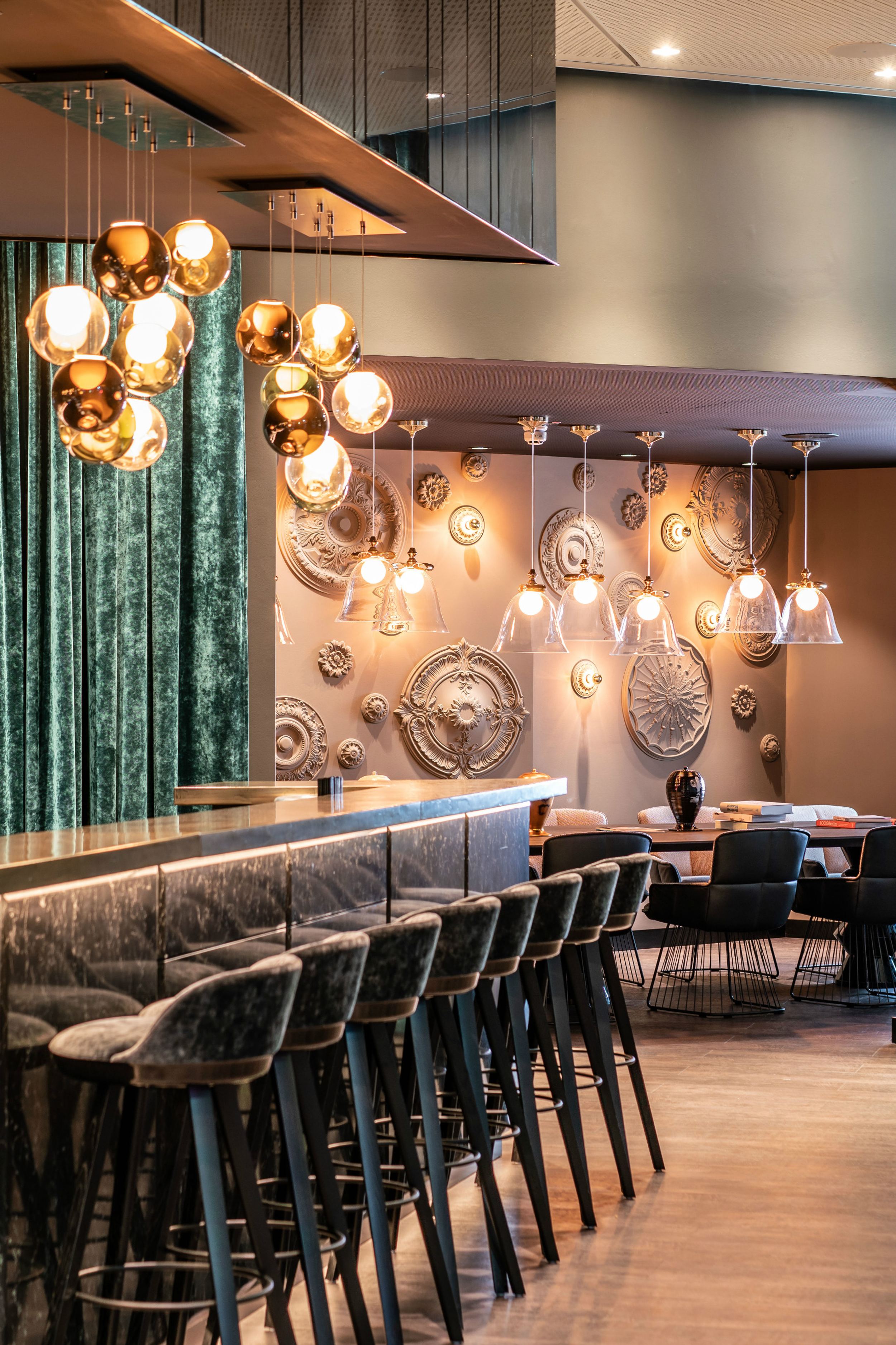 Designhotel Berlin Ku’damm Motel One helle Bar mit langer Theke und mehreren Barhockern sowie weitere Sitzgelegenheiten im Hintergrund