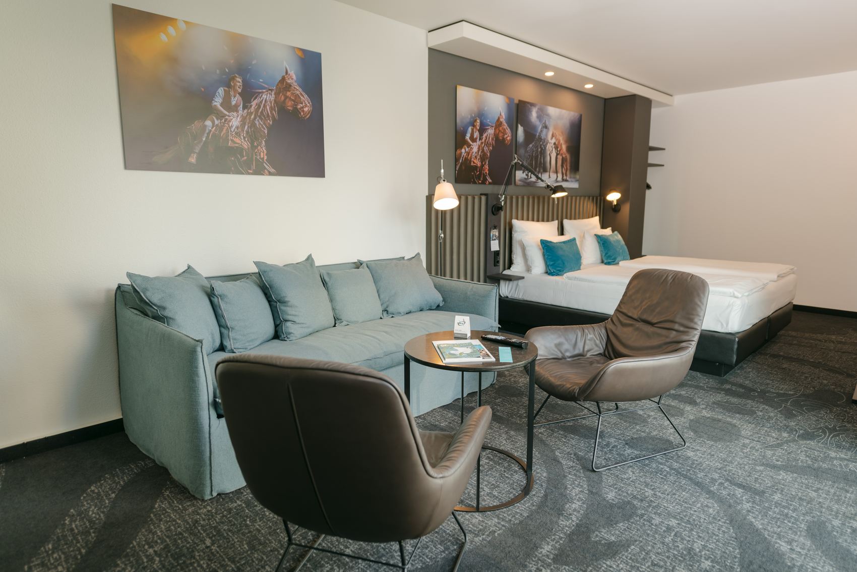 Designhotel Berlin Ku’damm Motel One großes Zimmer mit Doppelbett, Sofa und zwei Sesseln
