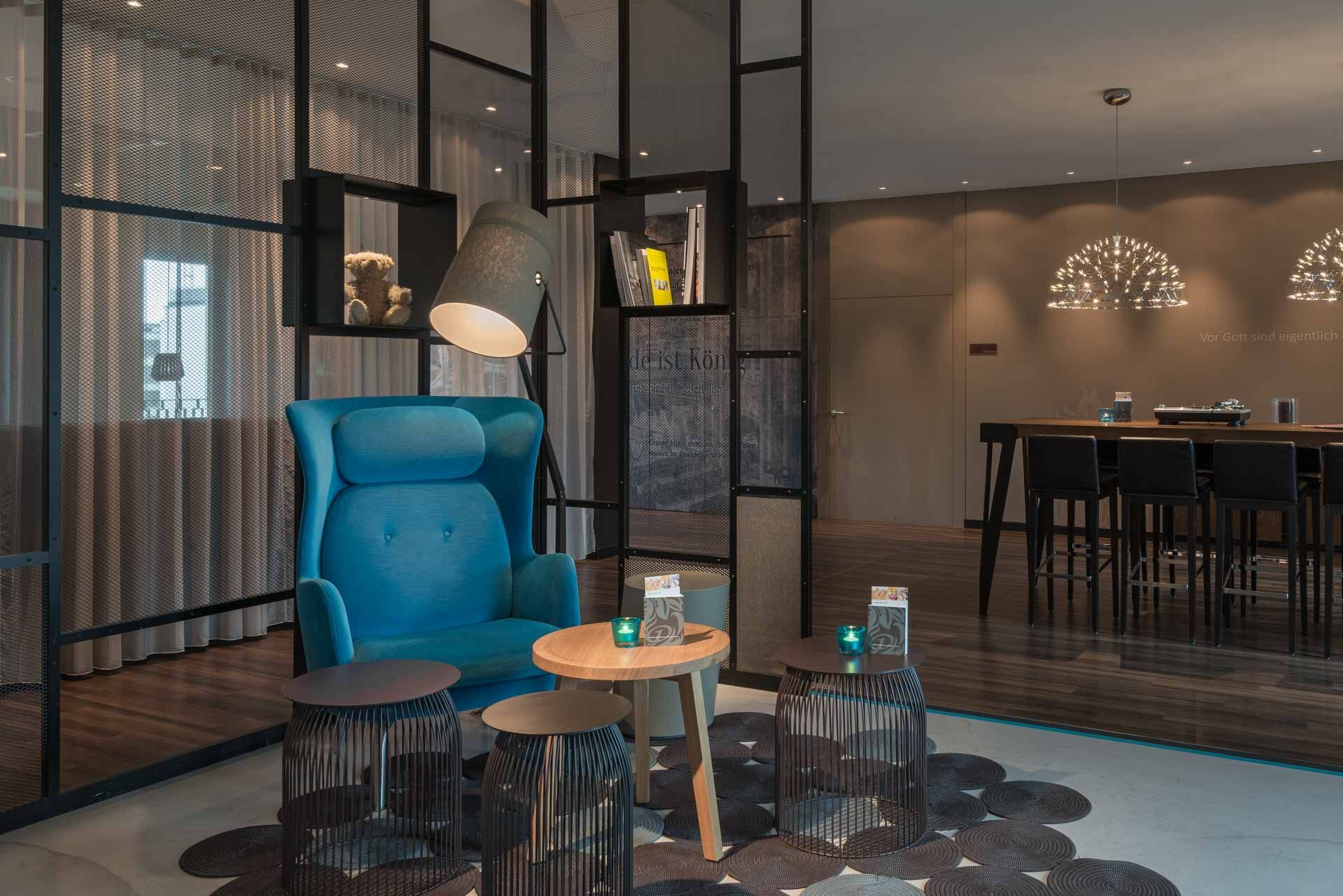 Hotel Berlin Potsdamer Platz Motel One Lounge mit Egg Chair im Vordergrund sowie einem hohen Tisch und Stühlen im Hintergrund