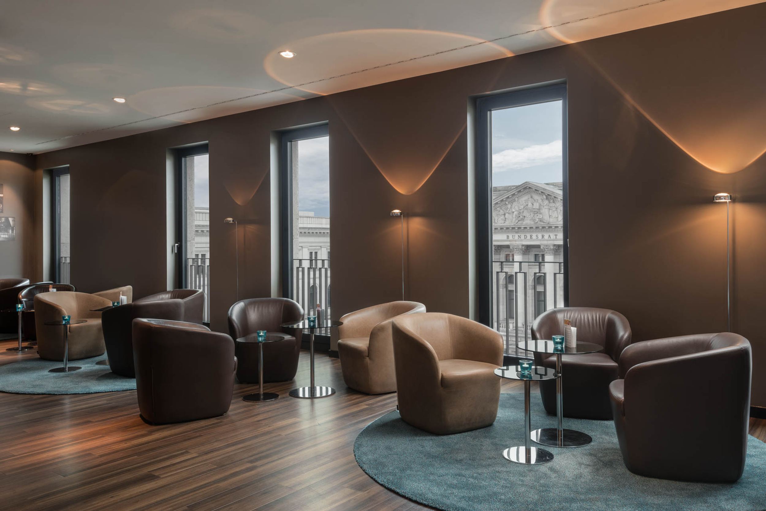 Designhotel Berlin Potsdamer Platz Motel One helle Lounge mit bodentiefen Fenstern sowie mehreren Sesseln und Beistelltischen