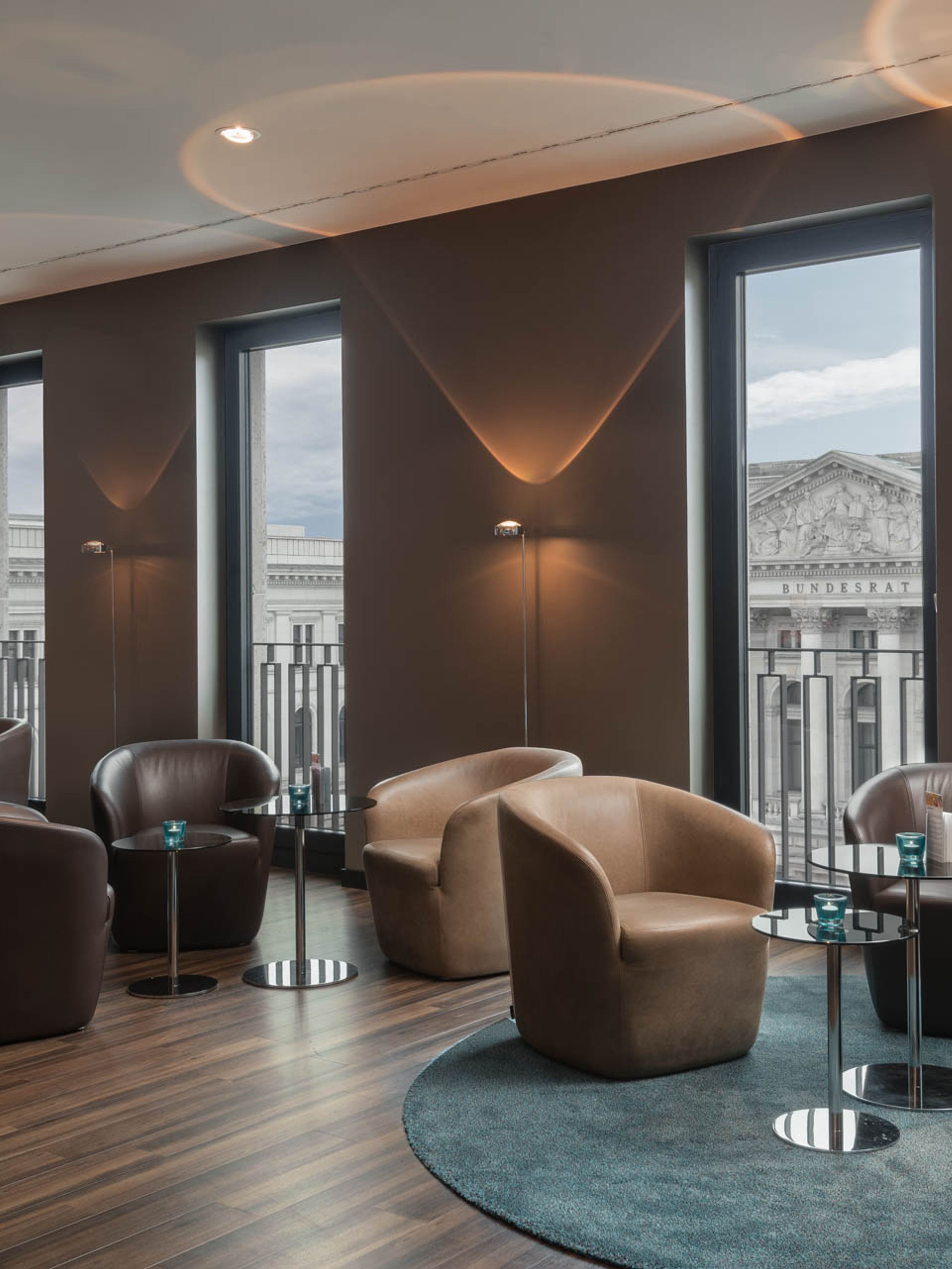 Designhotel Berlin Potsdamer Platz Motel One helle Lounge mit bodentiefen Fenstern sowie mehreren Sesseln und Beistelltischen