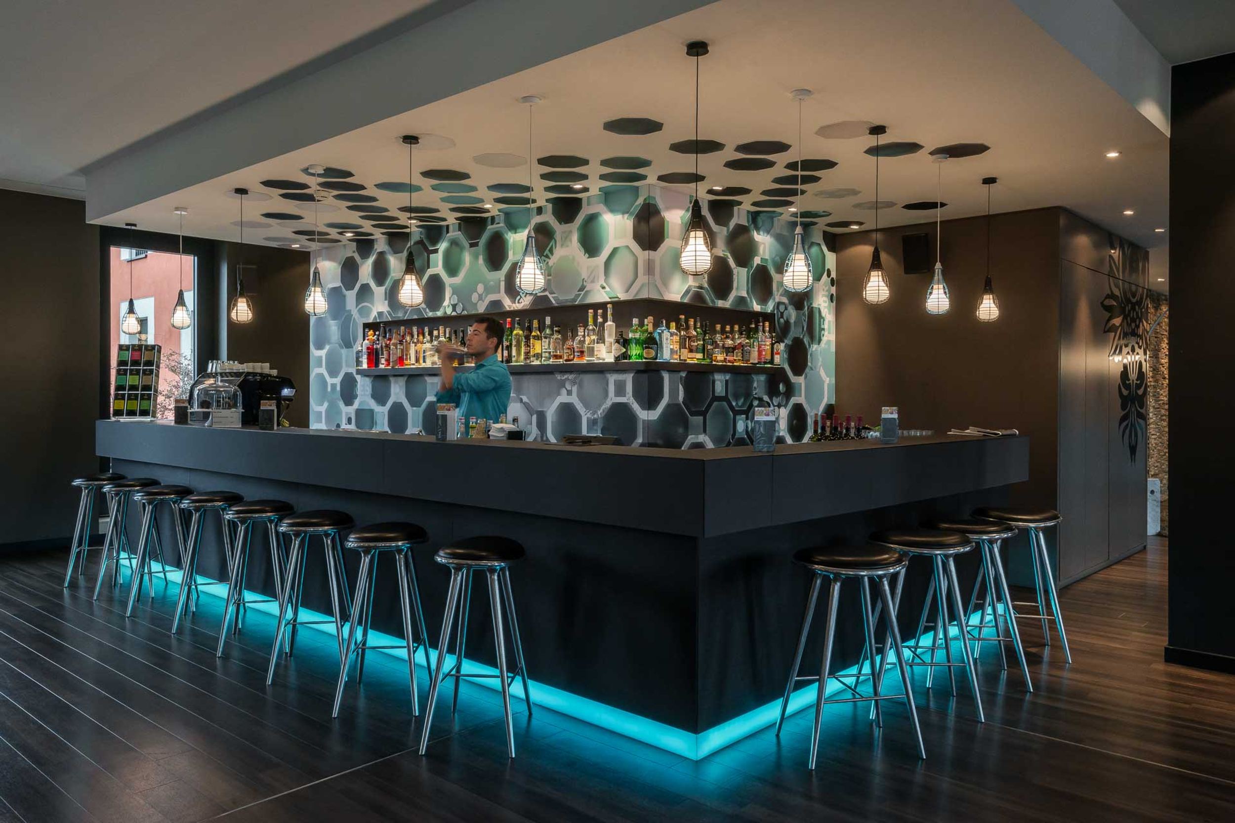 Hotel Berlin Potsdamer Platz Motel One Bar mit mehreren Barhockern sowie einem Barkeeper beim Shaken eines Cocktails