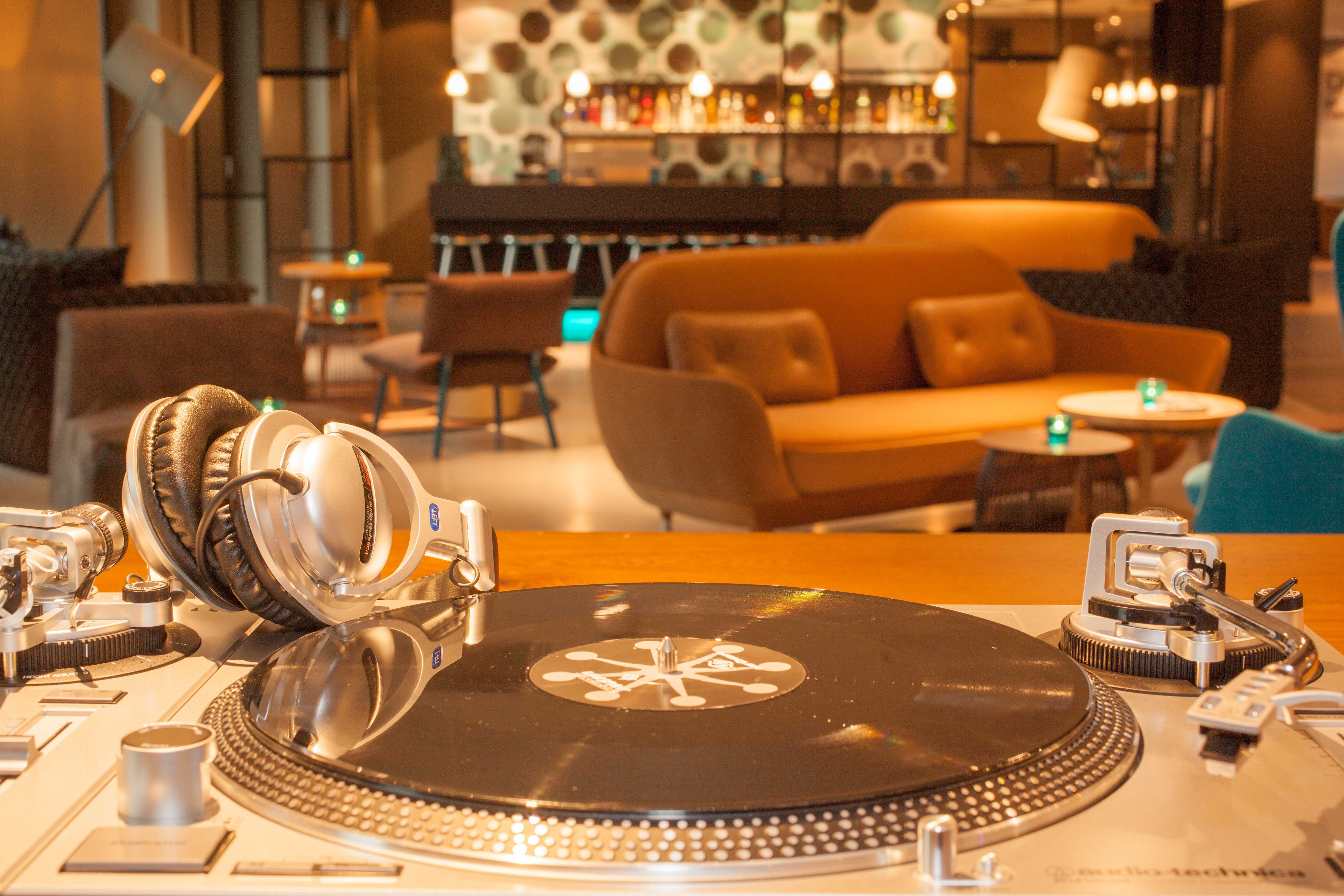 Hotel Berlin Potsdamer Platz Motel One Nahaufnahme Schallplattenspieler und Kopfhörer in großer Lounge und Bar im Hintergrund