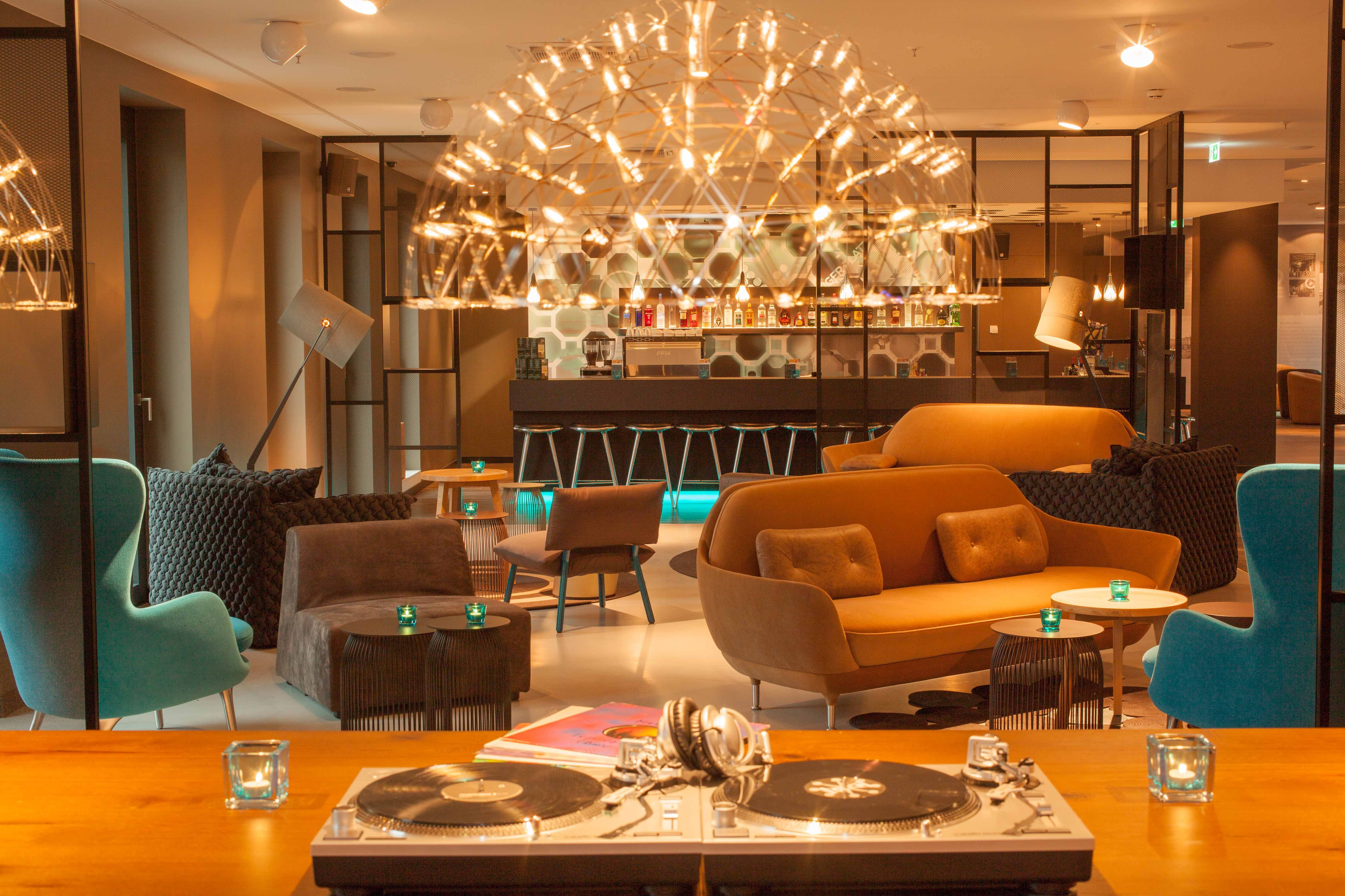 Hotel Berlin Potsdamer Platz Motel One große Lounge mit mehreren Sesseln, Sofas und Beistelltischen sowie Bar