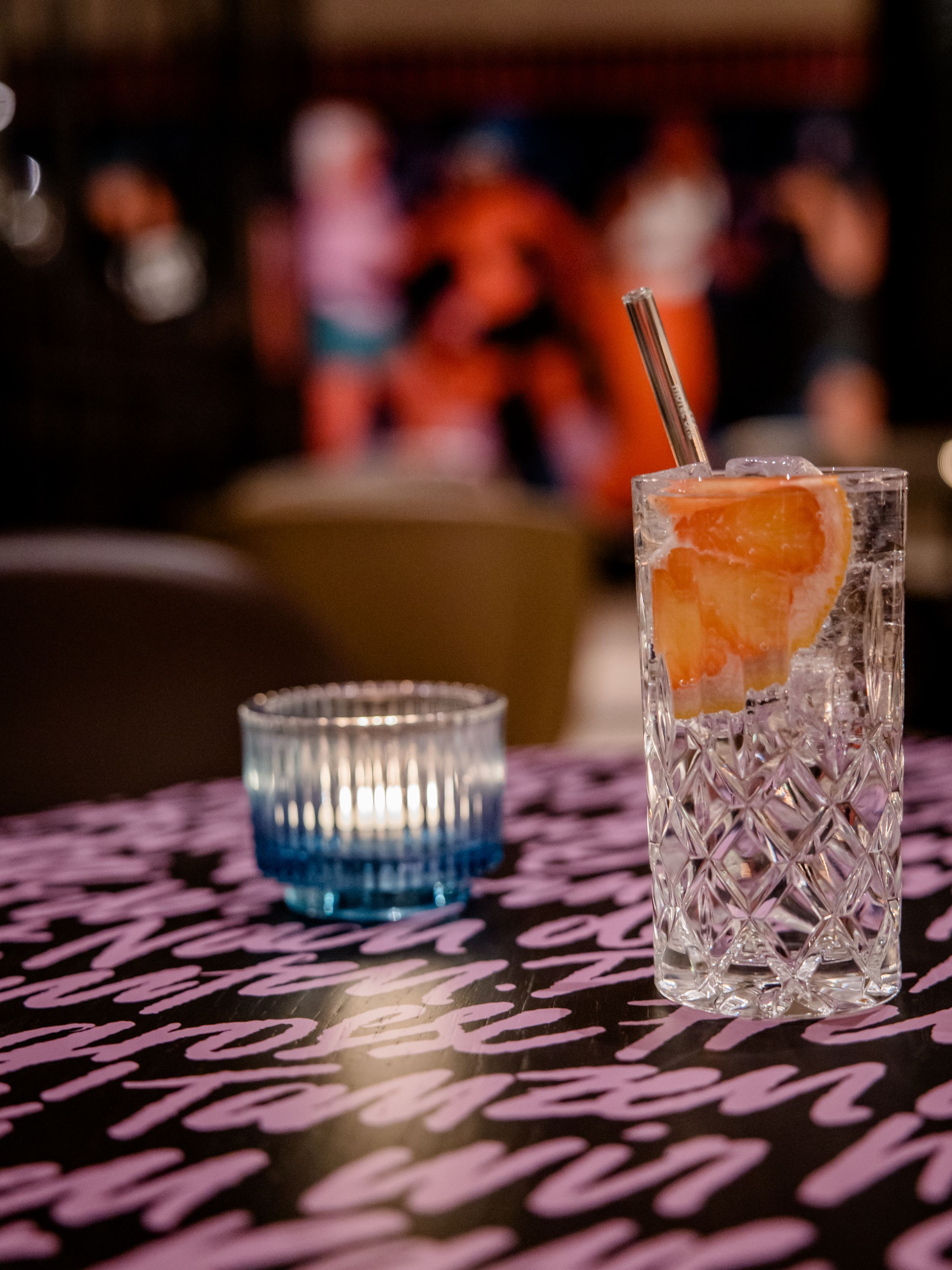 Hotel Berlin-Potsdamer Platz Motel One und ein erfrischendes Getränk mit Eis und Grapefruitscheibe steht auf einem Tisch neben einer kleinen, brennenden Kerze