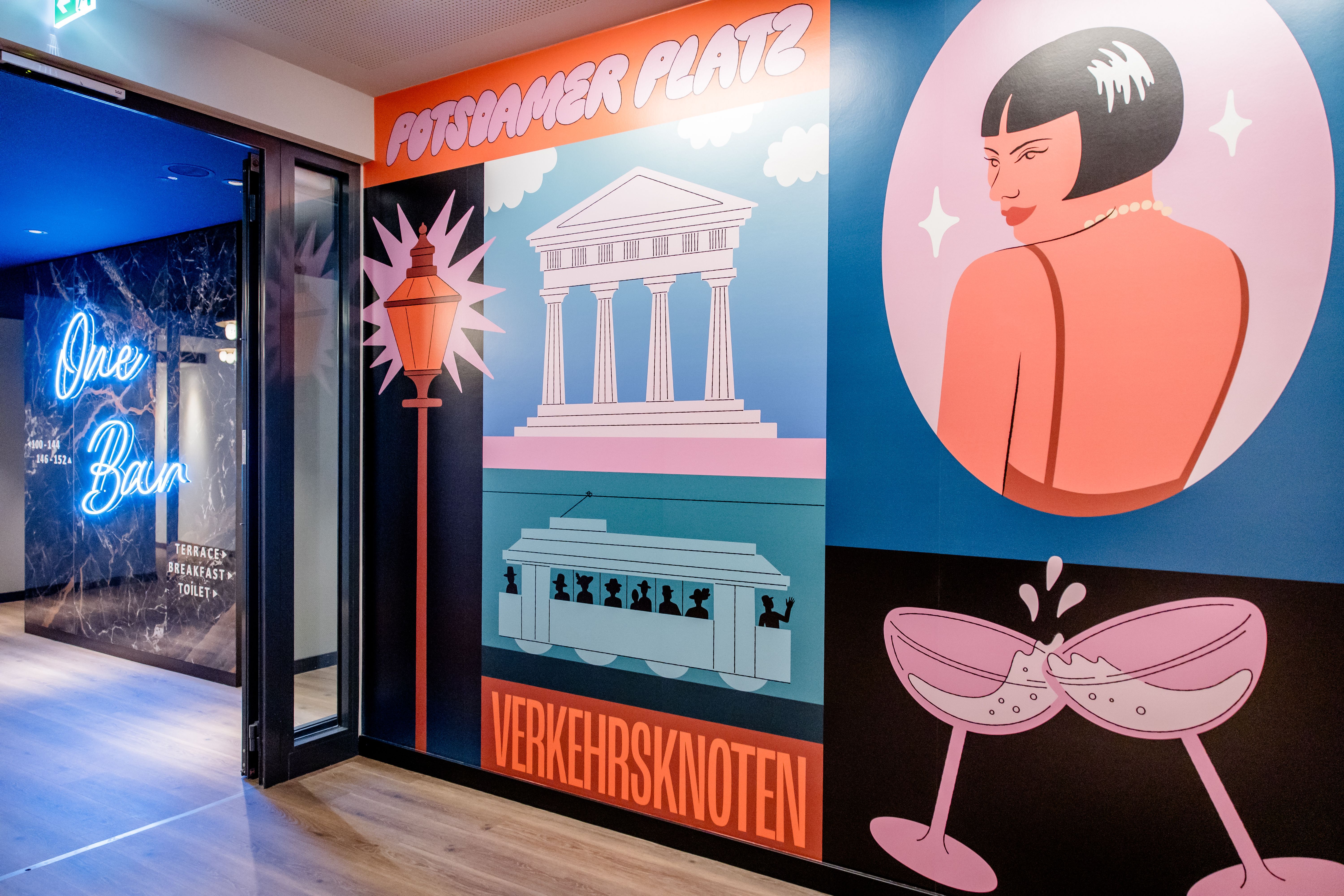 Hotel Berlin-Potsdamer Platz Motel One bunte Wandgestaltung mit Illustrationen eines Tempels, einer Straßenlampe, einer Straßenbahn, einem stilisierten Porträt einer Frau und zwei anstoßenden Sektgläsern, daneben Eingang zu einer Bar mit blauem Neonlicht „One Bar“.