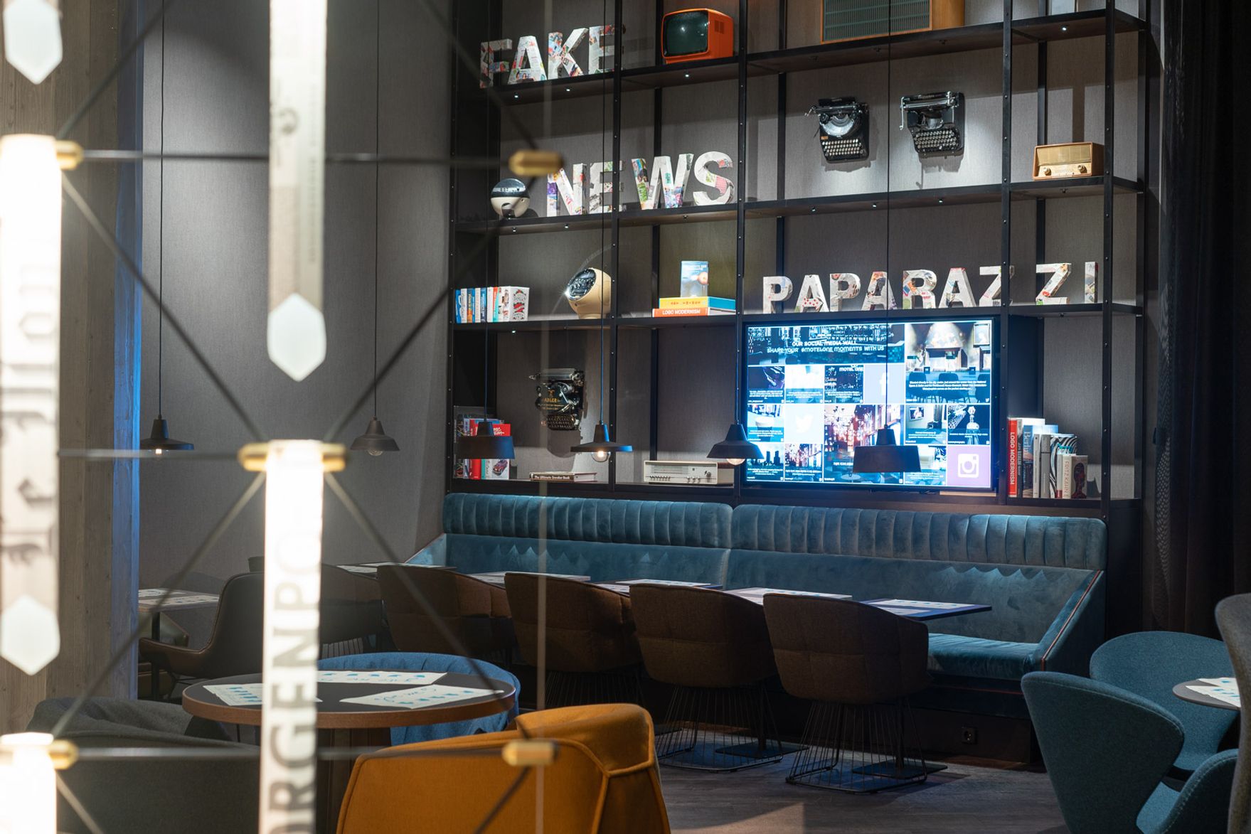 Hotel Berlin Spittelmarkt Motel One große Lounge mit offenem Regal mit Dekoration und Sofas sowie Sessel zum Verweilen