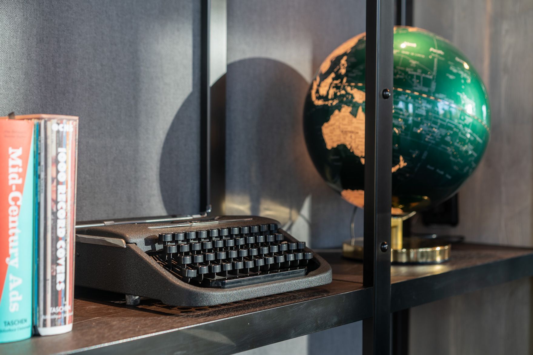 Designhotel Berlin Spittelmarkt Motel One Blick in ein offenes Regal mit Weltkugel, alter Schreibmaschine und Bücher